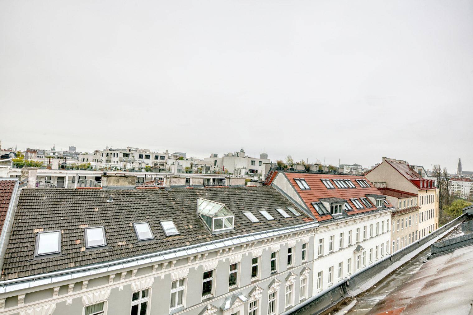 Blick über die Dächer der Stadt mit verschiedenen Gebäudefassaden und Dachfenstern.