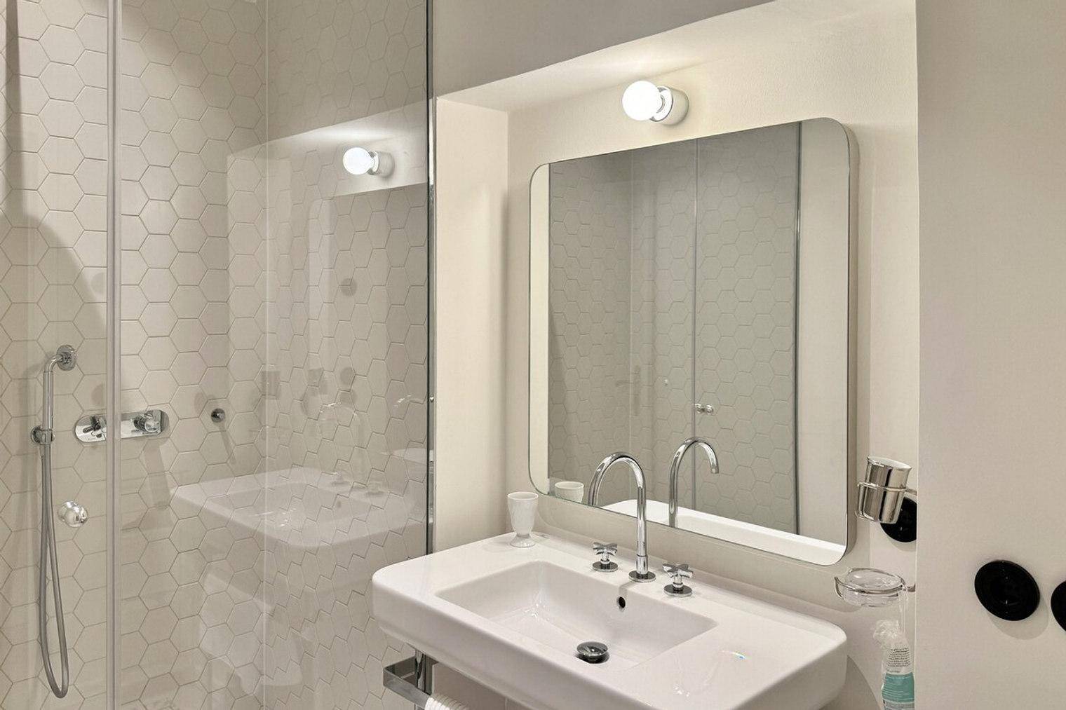 Modernes Badezimmer mit begehbarer Dusche, sechseckigen Fliesen und elegantem Waschbecken.