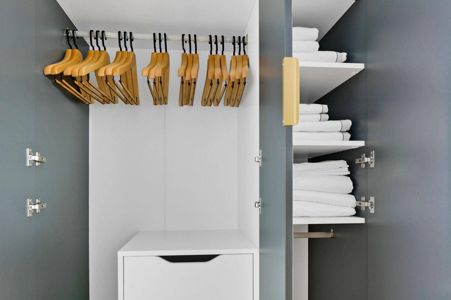 Offener Kleiderschrank mit Kleiderbügeln und Regalen für Wäsche.