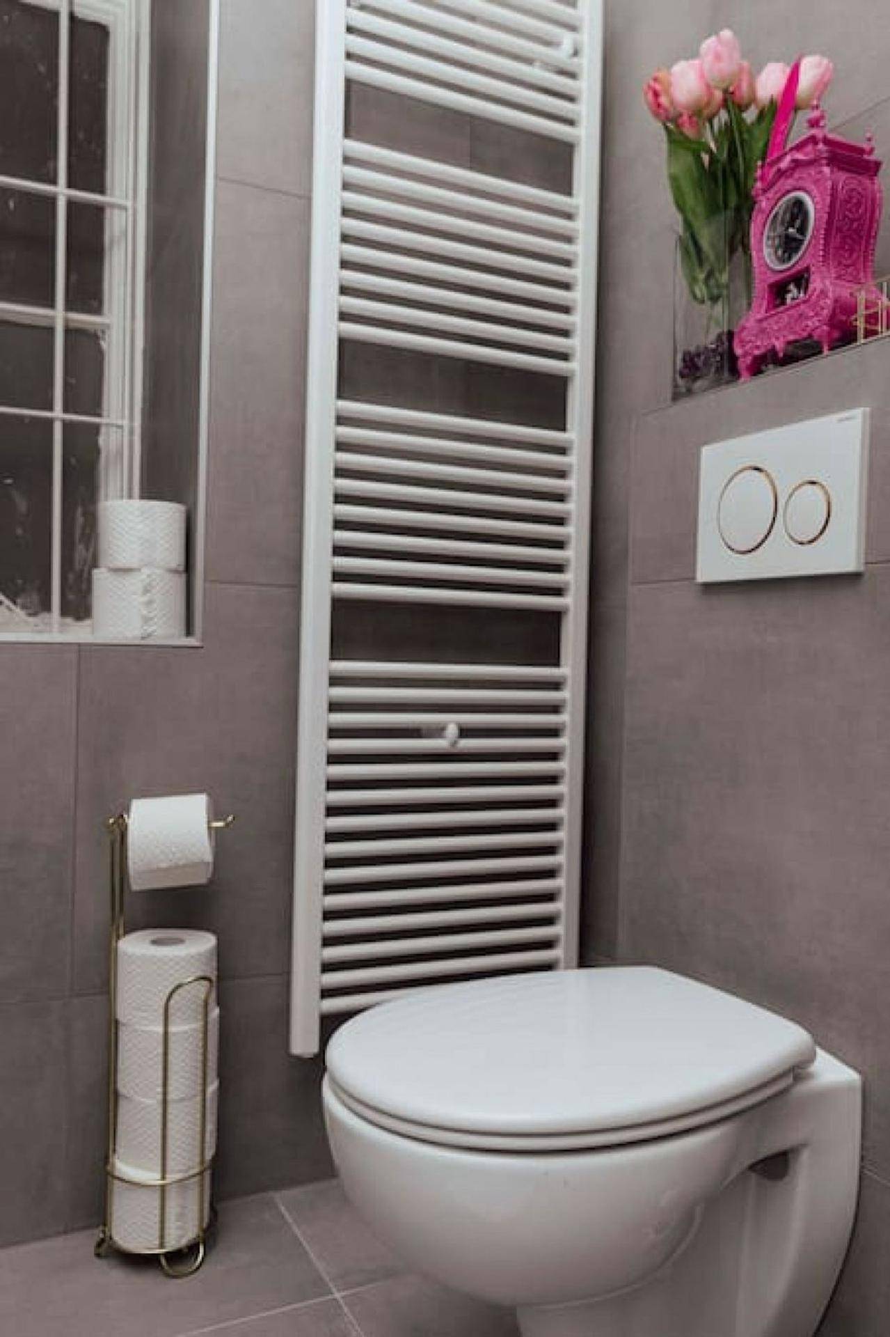 Modernes WC mit Wandtoilette, beheiztem Handtuchhalter und einem Fenster für natürliches Licht.