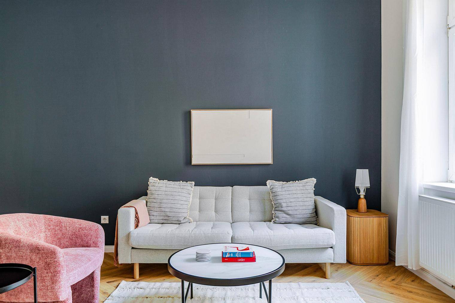 Gemütlicher Wohnbereich mit beigem Sofa, rosa Sessel und modernem Couchtisch.