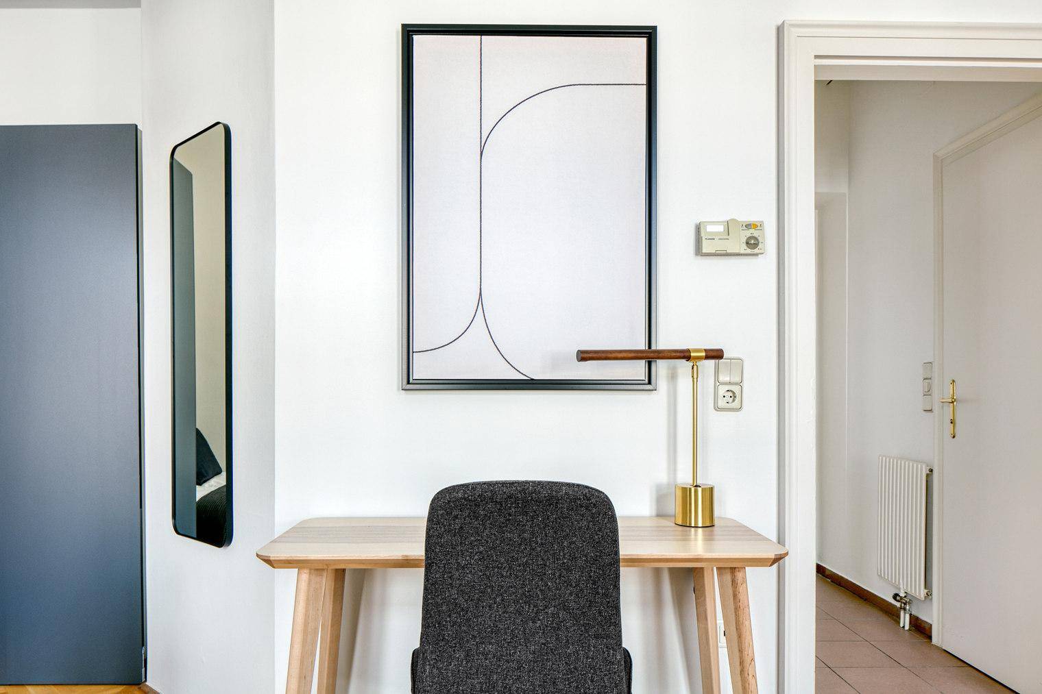 Kleiner Arbeitsbereich mit Schreibtisch, Stuhl und moderner Wanddekoration.