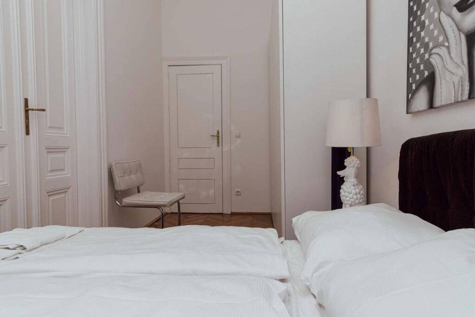 Schlafzimmer mit Doppelbett, weißer Bettwäsche und einer Nachttischlampe in Pudelform.