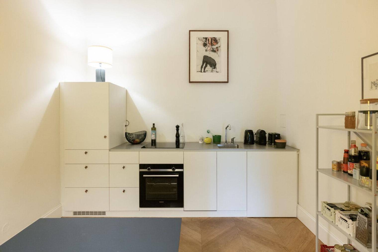 Funktionale Küchenzeile mit weißen Schränken, integriertem Backofen und praktischen Regalen.