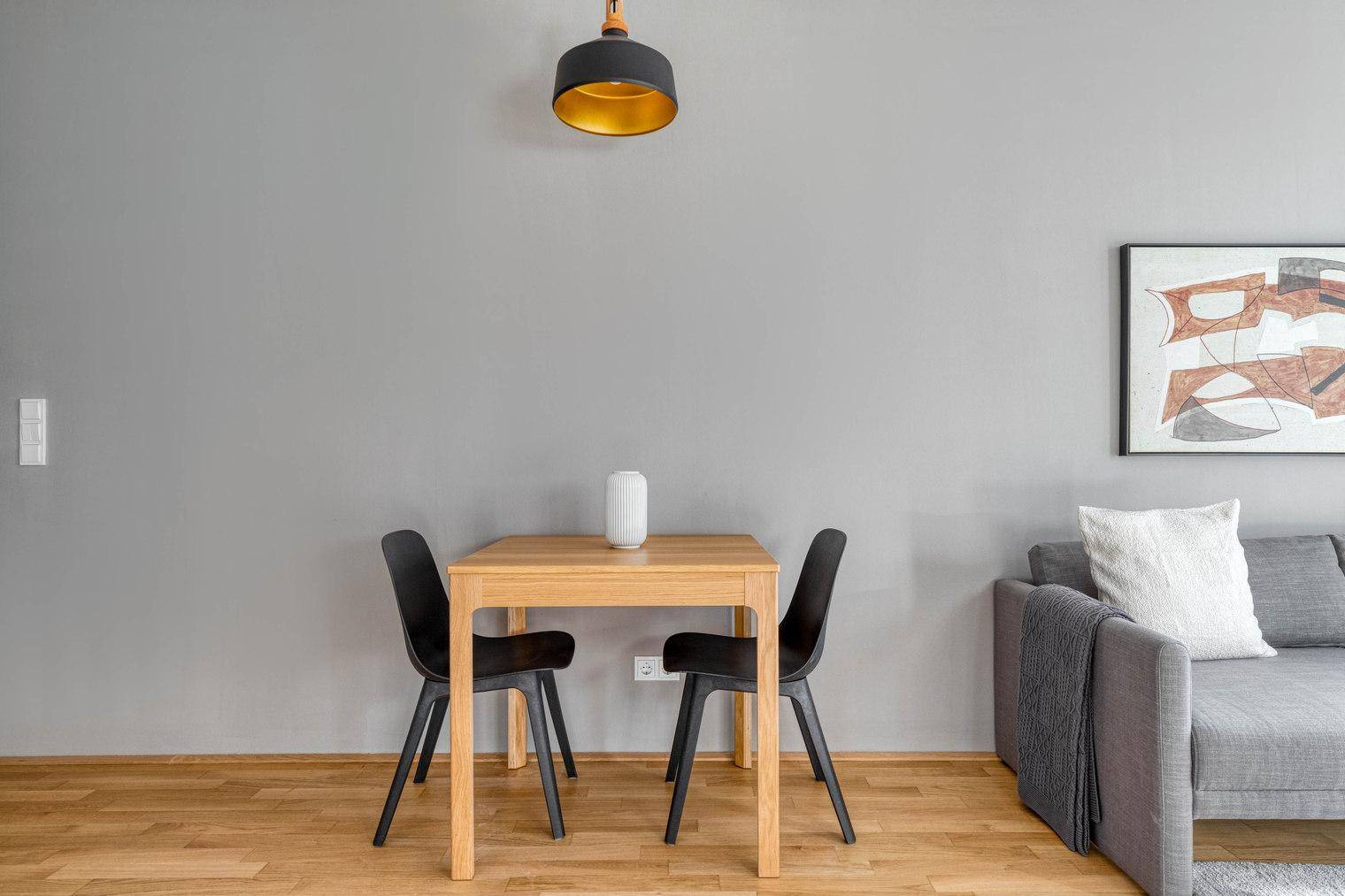 Kleiner Essbereich mit Holztisch und zwei Stühlen in einem modern eingerichteten Raum.