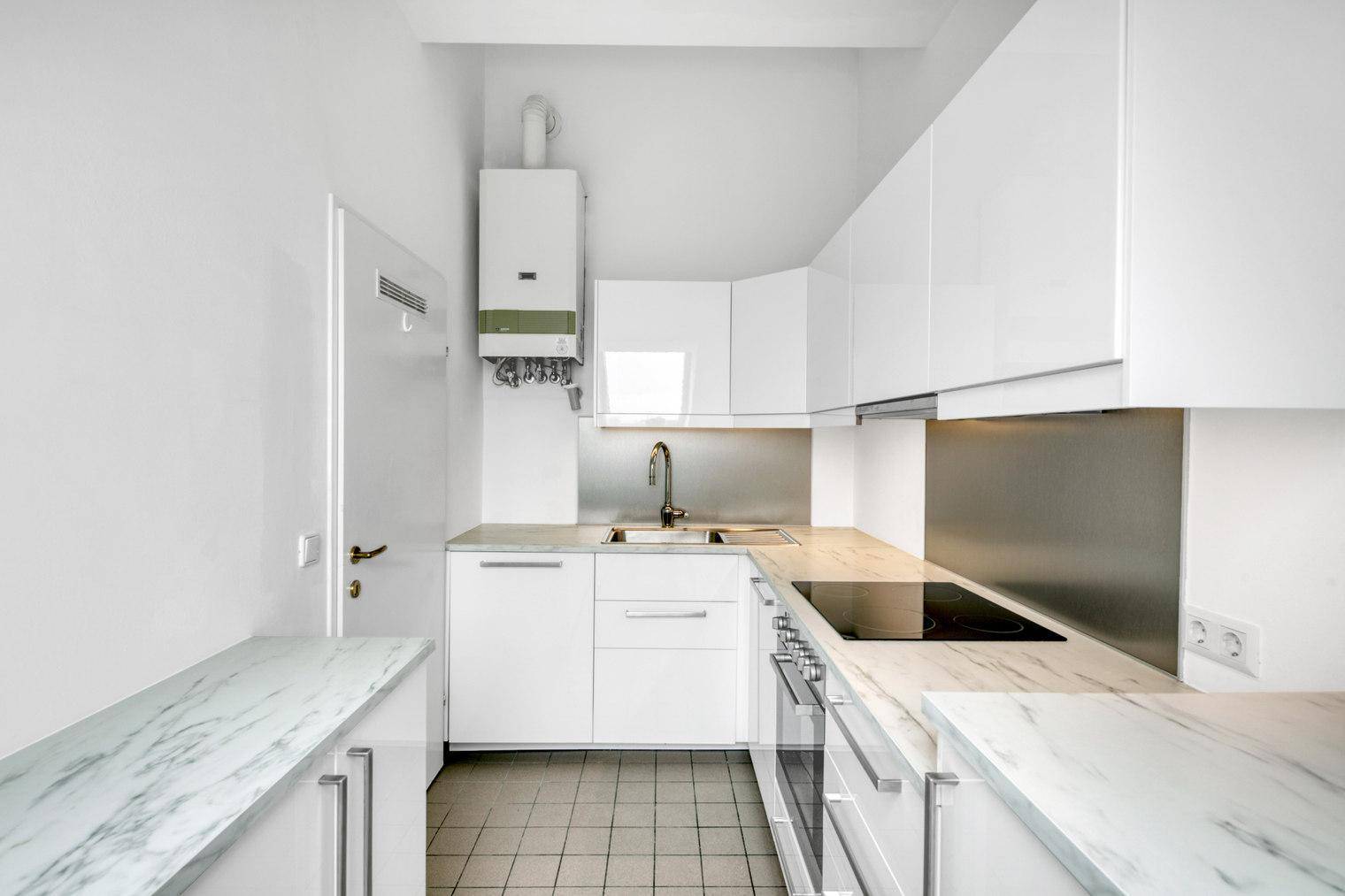 Kompakte, moderne Küche mit weißen Hochglanzfronten, Spüle und Gastherme.