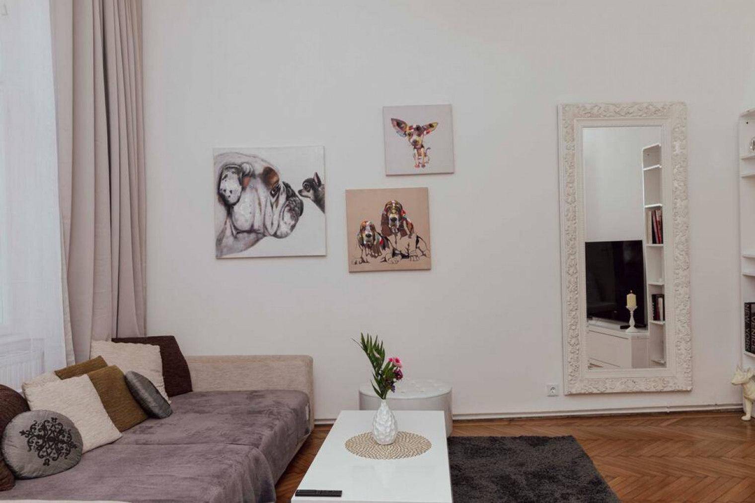 Wohnzimmer mit beigem Sofa, Couchtisch und dekorativen Tierbildern an der hellen Wand.