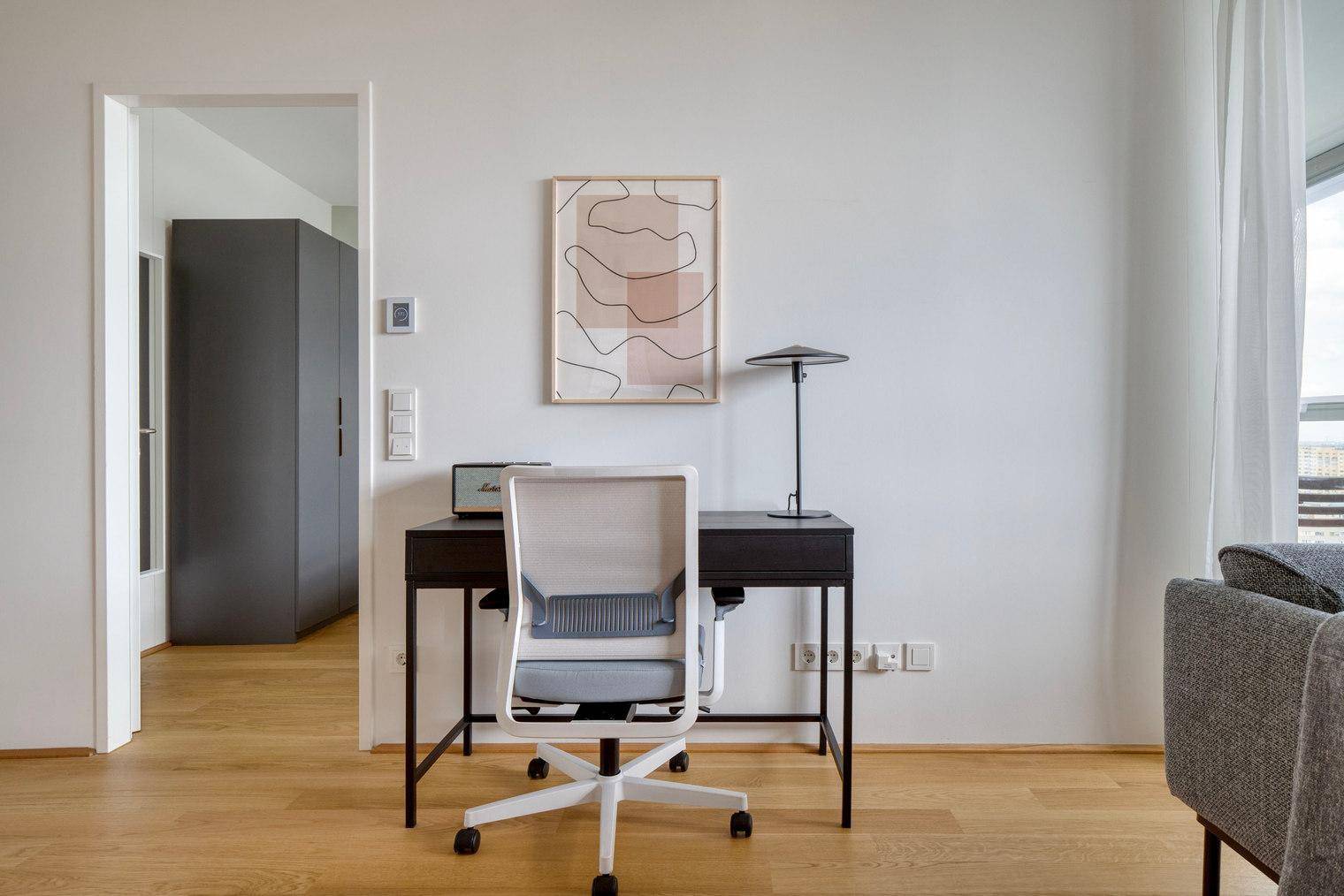 Kleiner Arbeitsbereich mit Schreibtisch und Bürostuhl in einem hellen Raum.