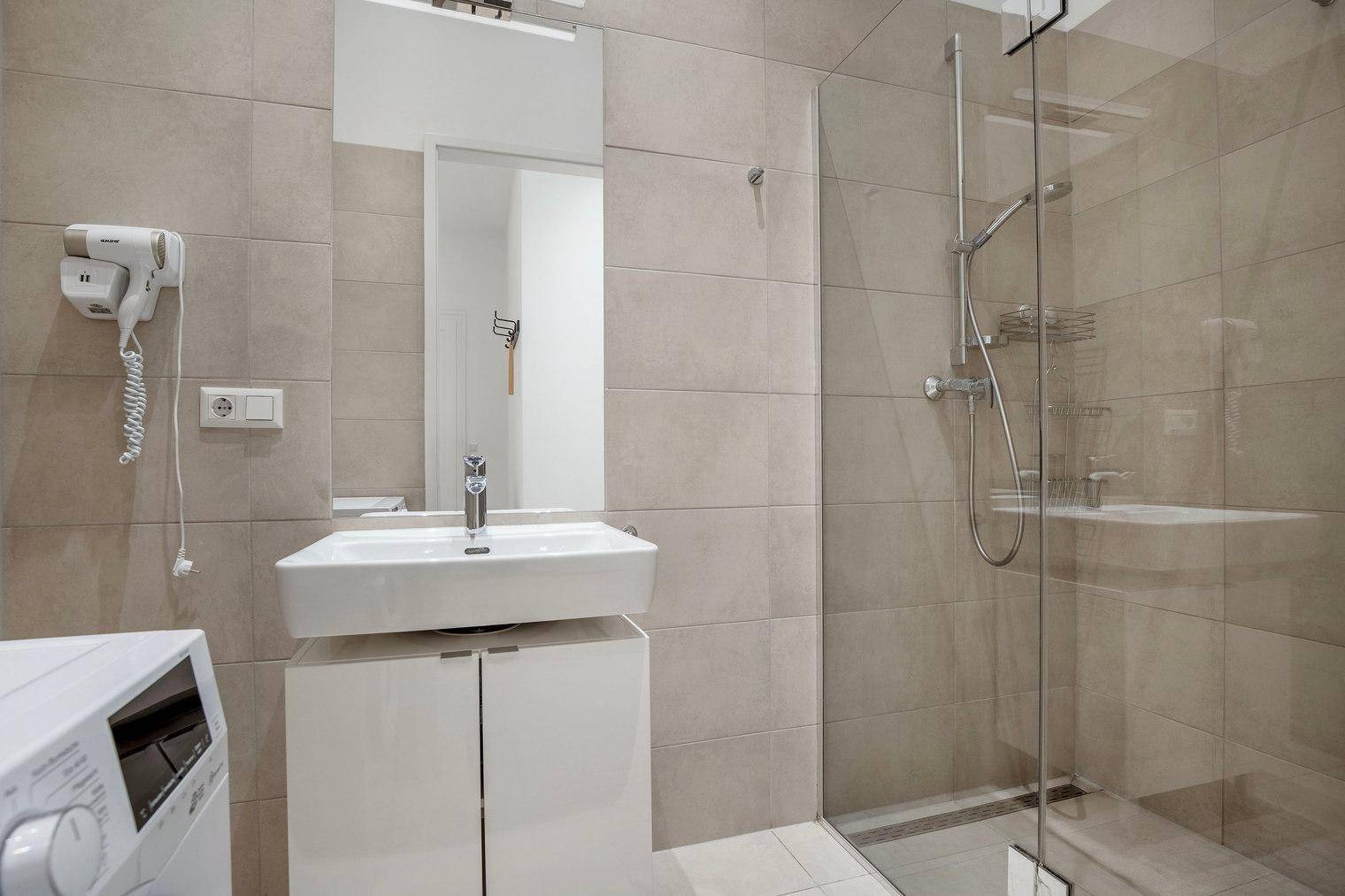 Modernes Badezimmer mit begehbarer Dusche, Waschbecken und Waschmaschine.