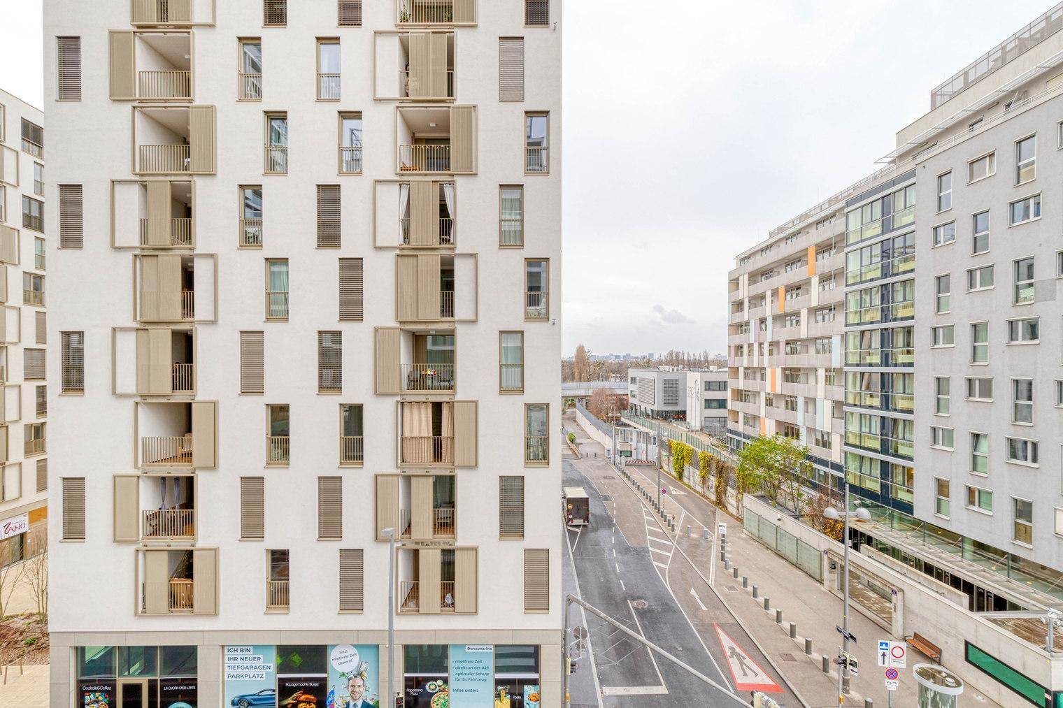 Moderne Wohngebäude mit vielen Fenstern und Balkonen entlang einer Straße.