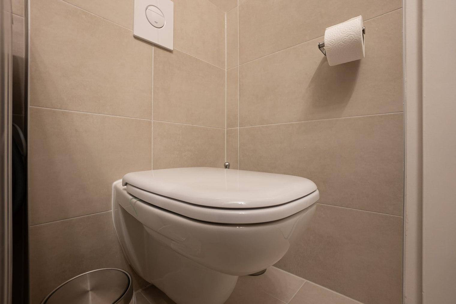 Wandmontiertes WC in einem modernen Badezimmer mit beigen Fliesen, platzsparend und hygienisch.