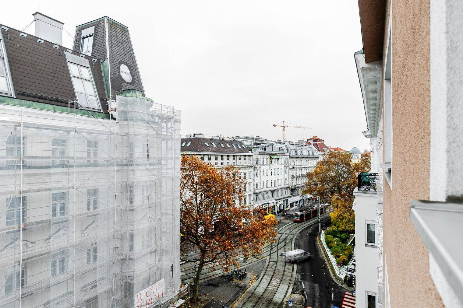 Panoramablick auf eine städtische Straße mit historischen Gebäuden und Herbstbäumen.