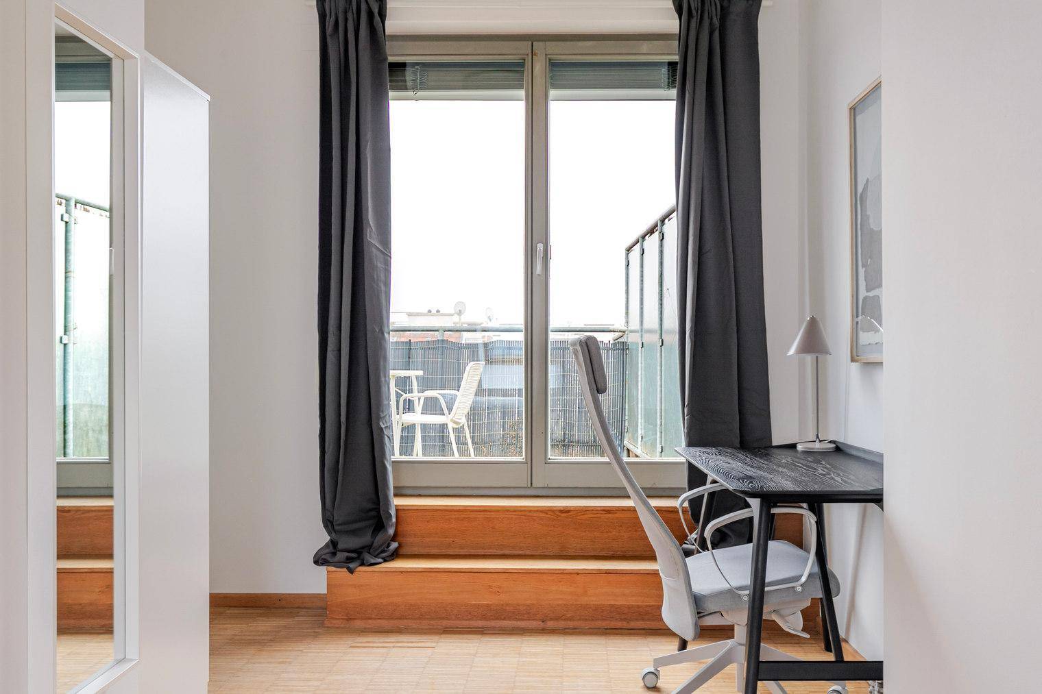 Helles Arbeitszimmer mit Zugang zu einem französischen Balkon und Blick nach draußen.
