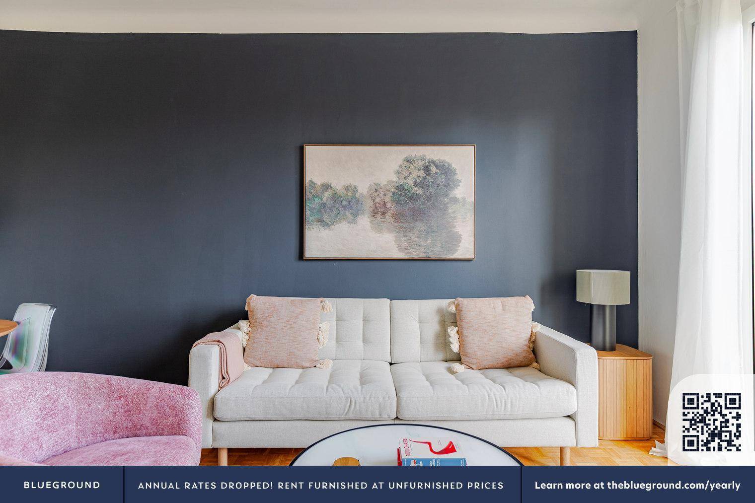 Detailansicht des Wohnzimmers mit bequemer Couch, Kunstwerk an der Wand und Beistelltisch.