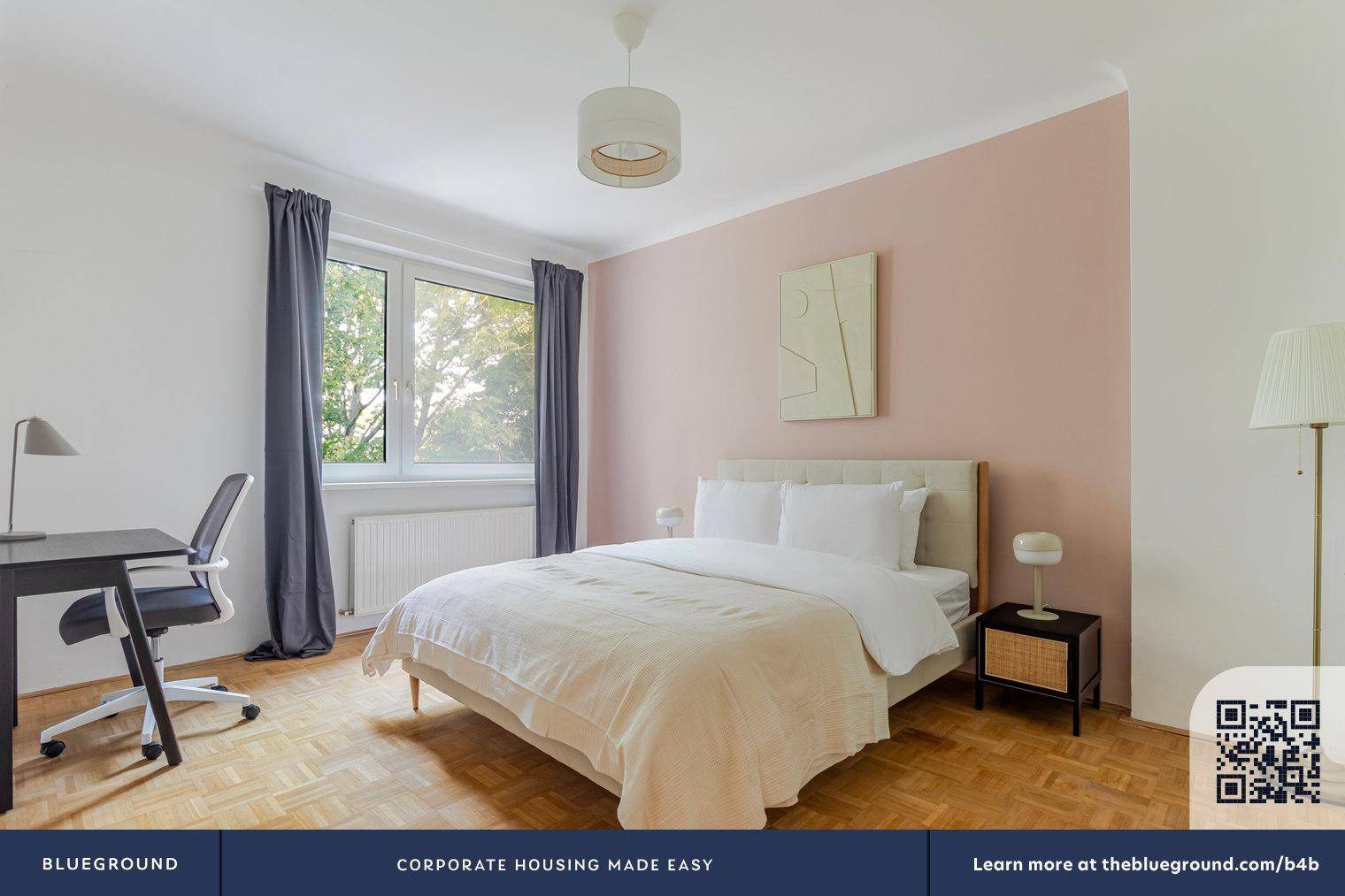 Helles Schlafzimmer mit Doppelbett, Schreibtisch und einer rosafarbenen Akzentwand.