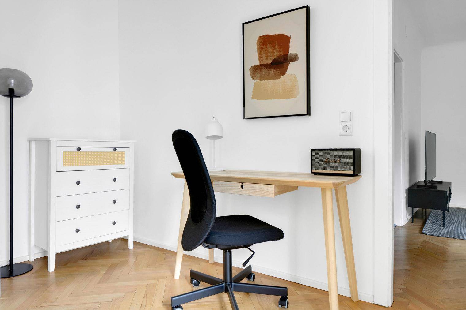 Heller Arbeitsbereich mit Schreibtisch, Bürostuhl und moderner Dekoration.