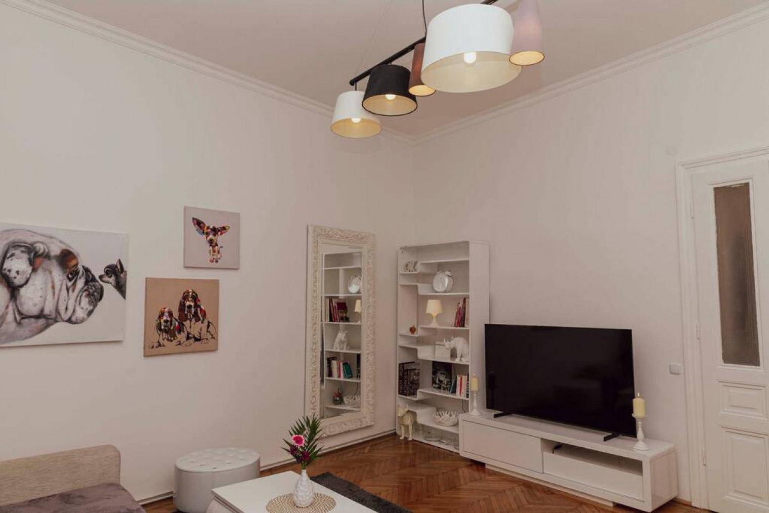 Gemütliches Wohnzimmer mit Fernseher, Bücherregalen und dekorativen Bildern an der Wand.