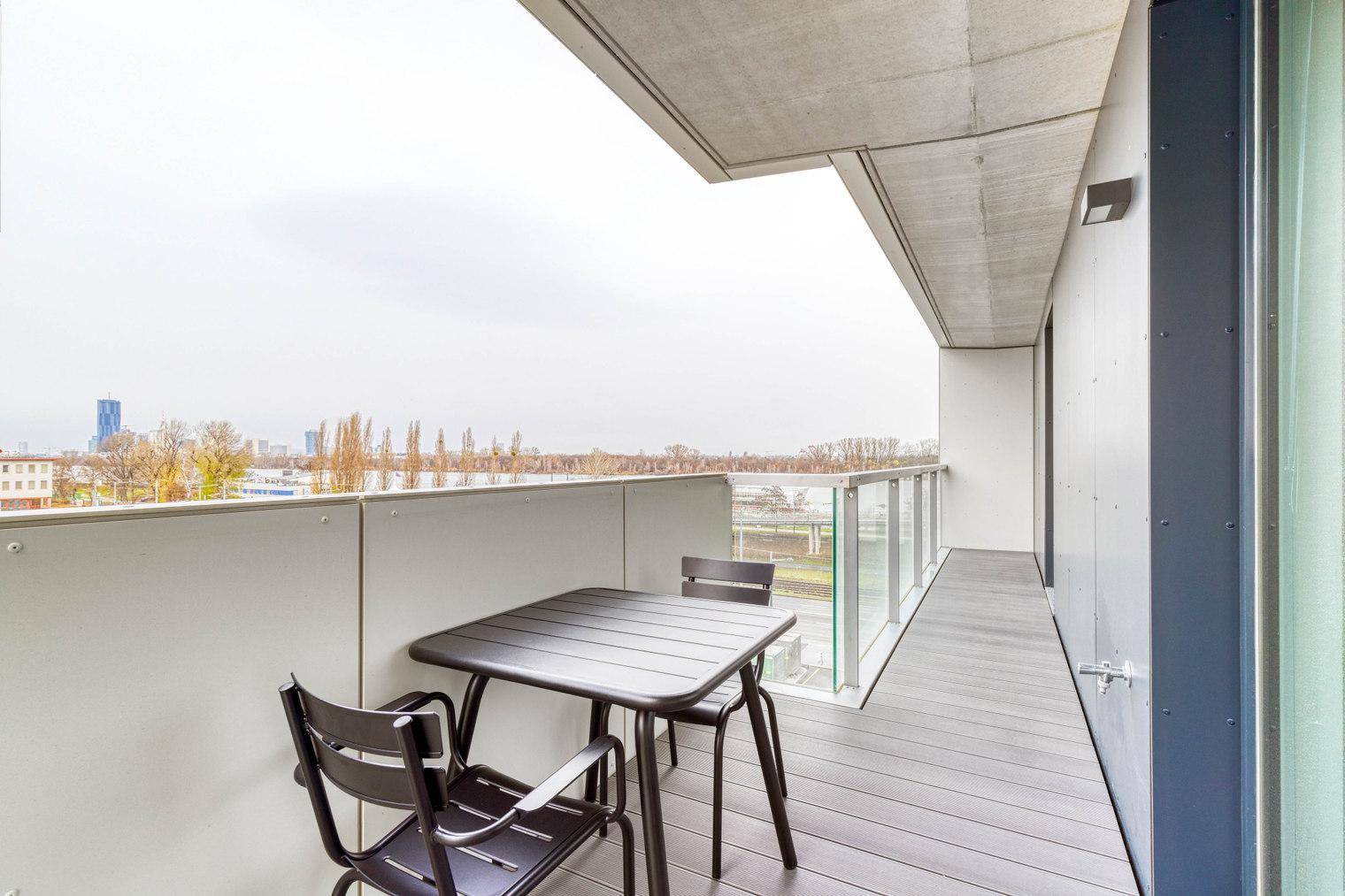 Geräumiger Balkon mit Sitzgelegenheiten und weitem Blick über die Stadt.