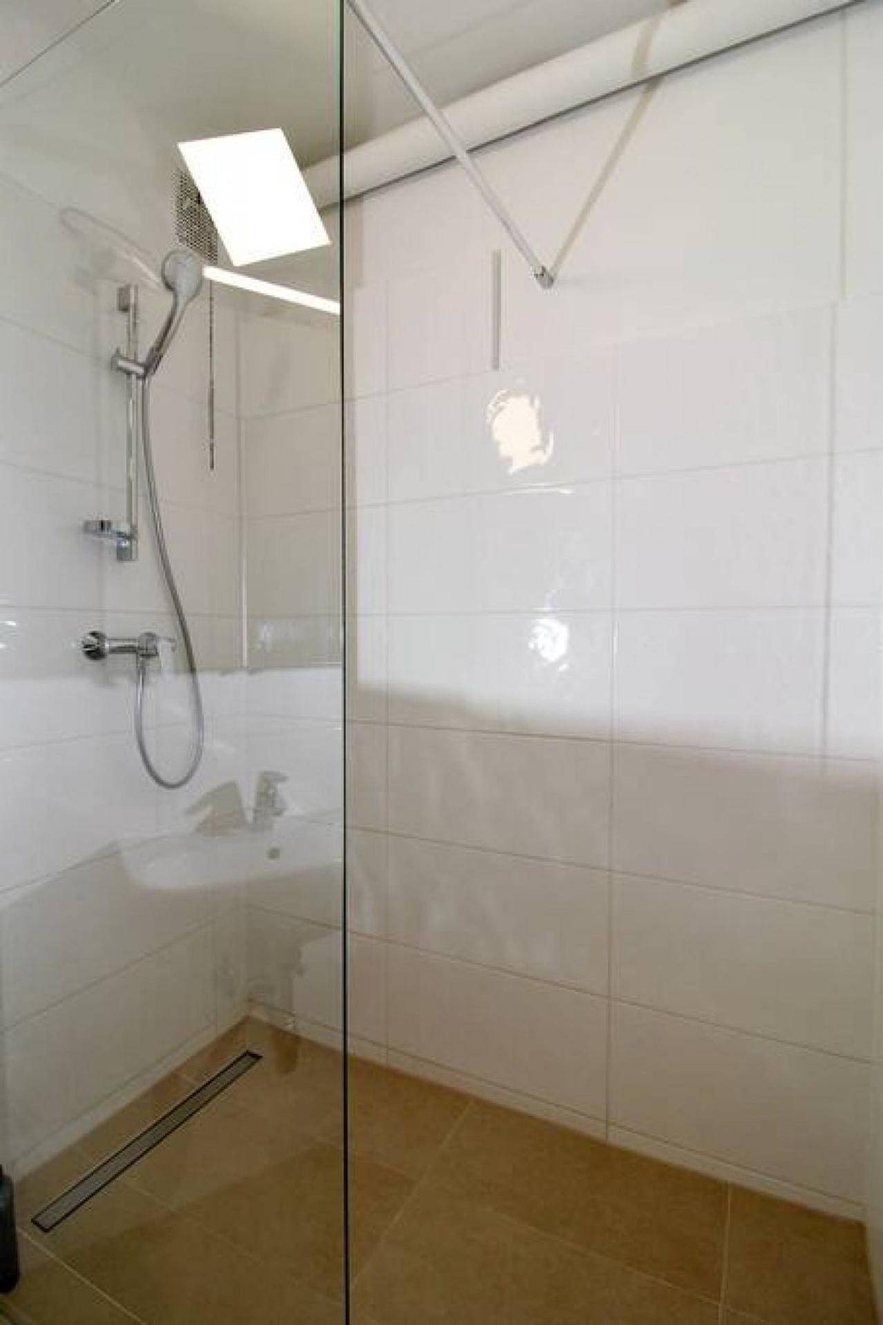 Ebenerdige Dusche mit Glasabtrennung und weißen Fliesen im Badezimmer.