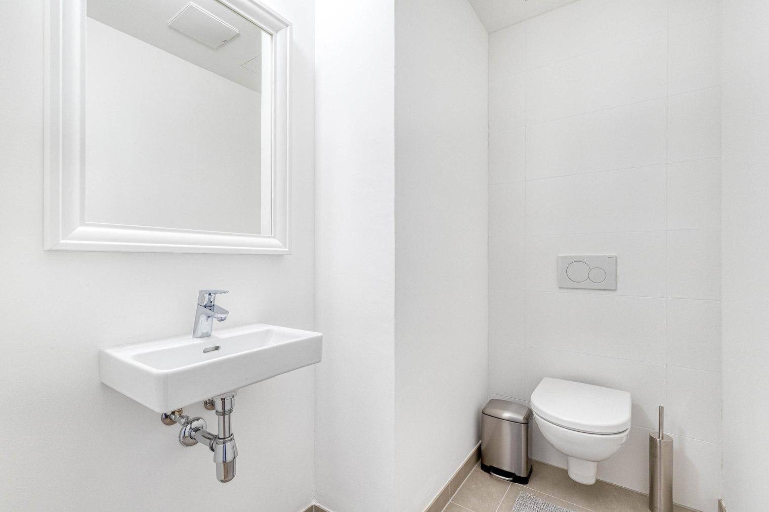 Modernes Gäste-WC mit wandhängender Toilette und kleinem Waschbecken.