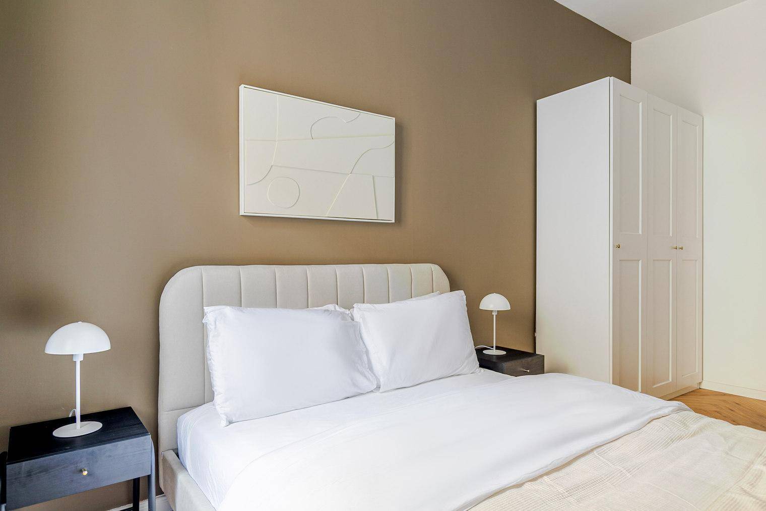 Schlafzimmer mit bequemem Doppelbett, Nachttischen und minimalistischer Wanddekoration.