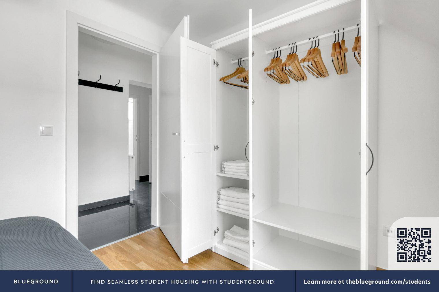 Offener Kleiderschrank mit viel Stauraum und Kleiderbügeln im Schlafzimmerbereich.