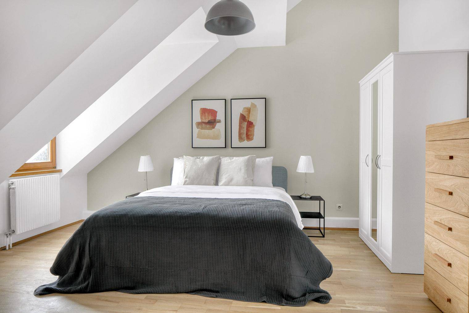 Schlafzimmer im Dachgeschoss mit Doppelbett, Holzboden und schrägen Wänden.