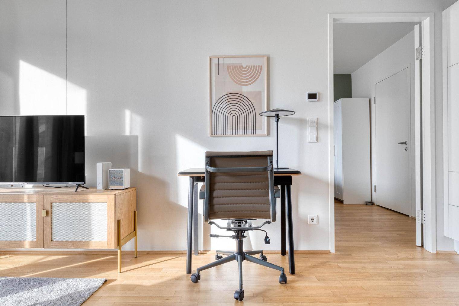Kleiner Arbeitsbereich mit modernem Schreibtisch und Bürostuhl in hellem Raum.