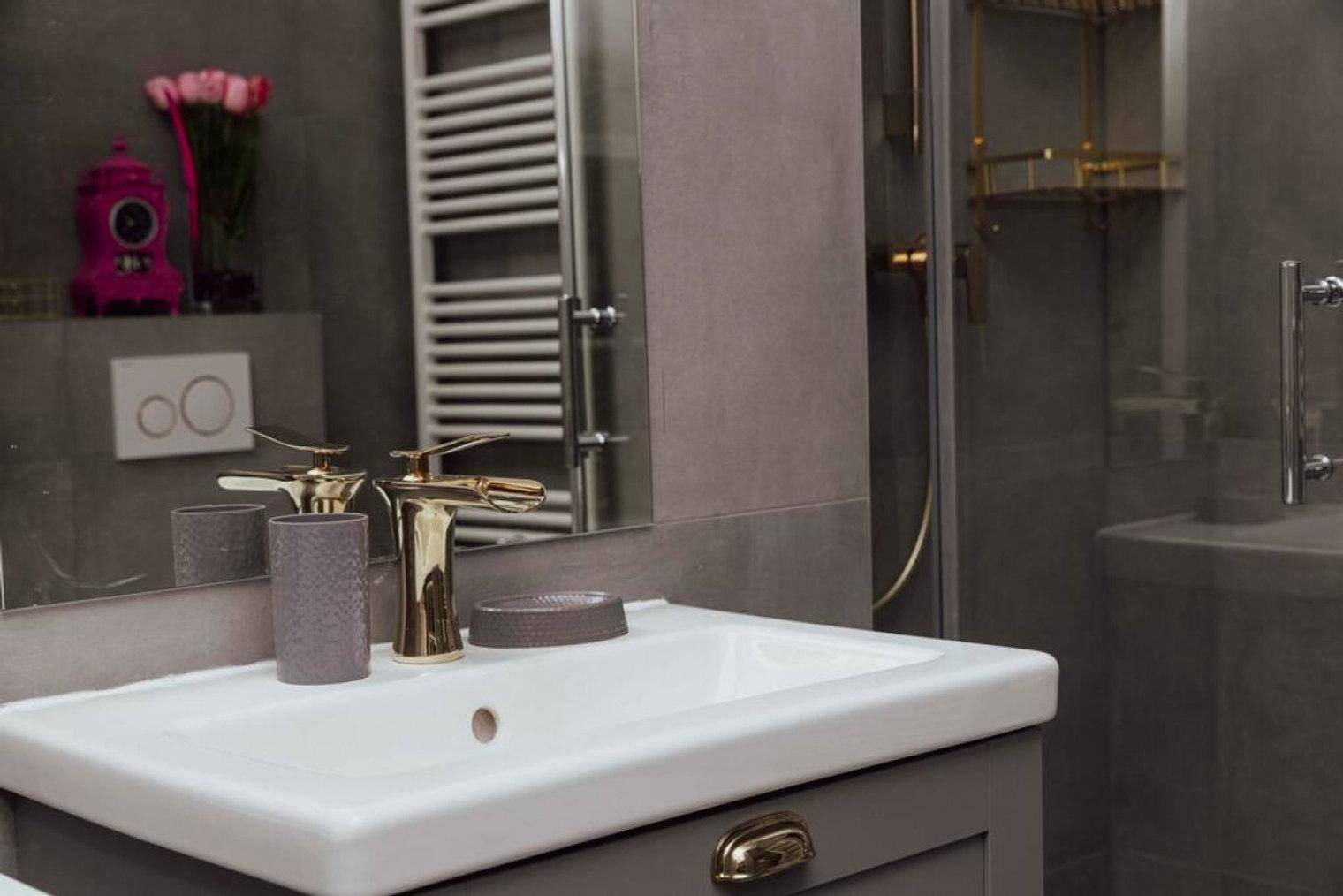 Modernes Badezimmer mit grauen Fliesen, Waschbecken und beheiztem Handtuchhalter.