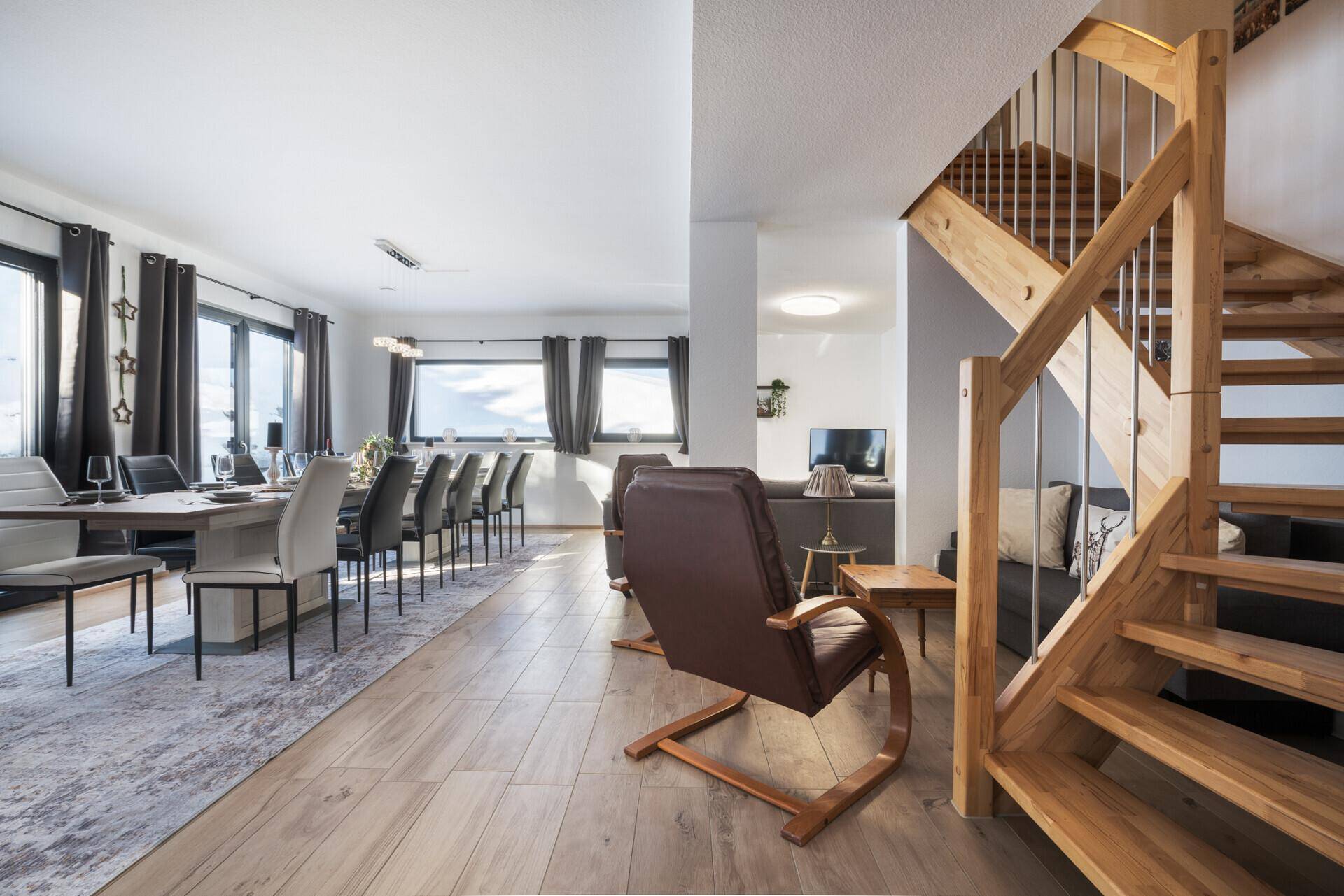 Heller, offener Wohn- und Essbereich mit Holzboden und moderner Holztreppe.