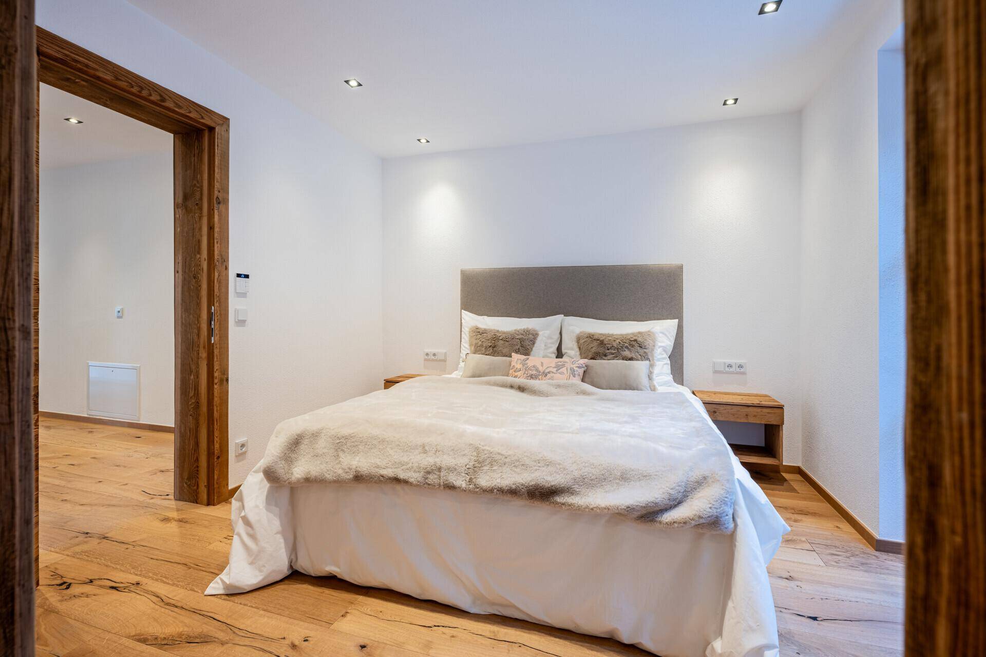 Helles Schlafzimmer mit Holzboden, weiß gestrichenen Wänden und modernem Doppelbett.