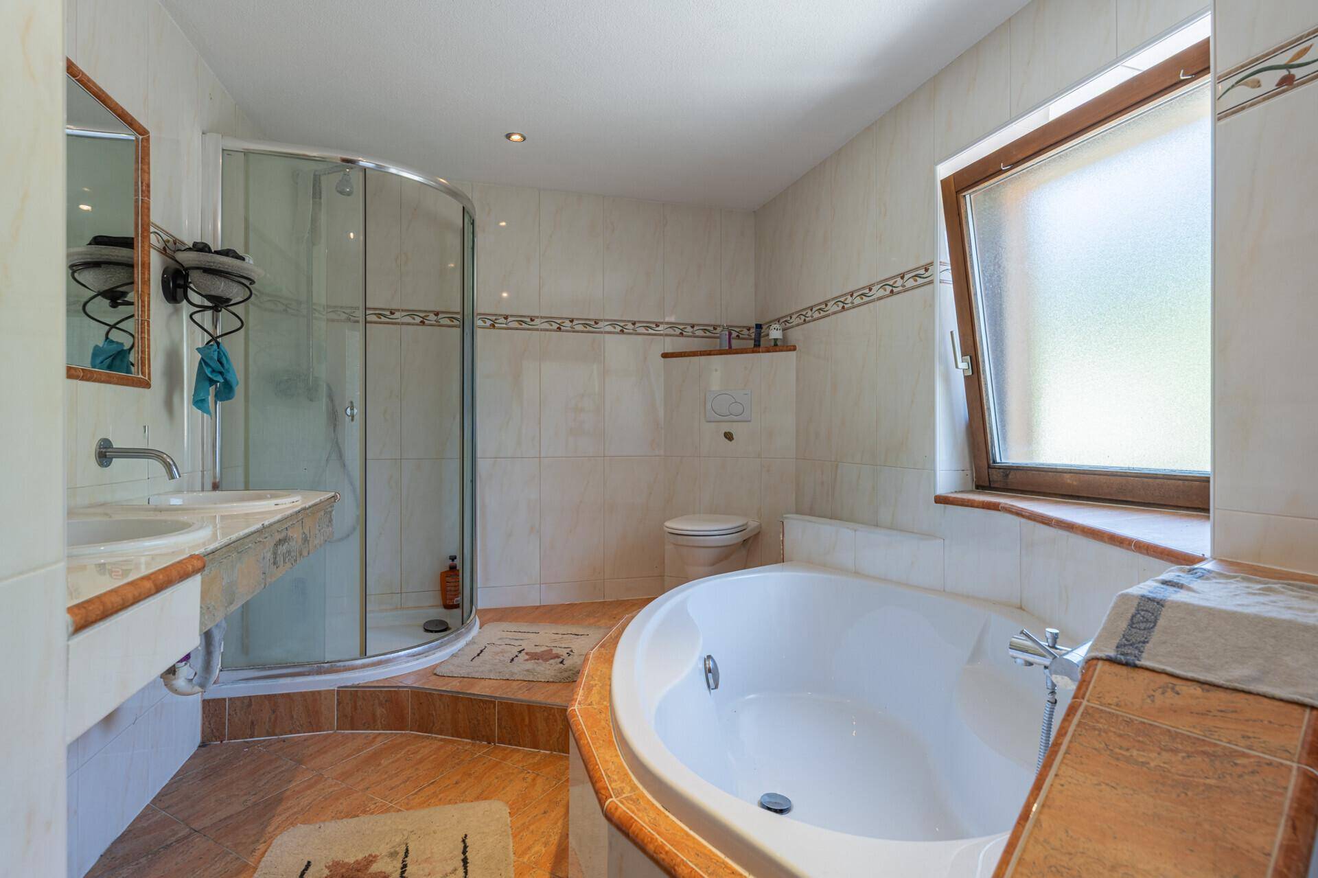 Geräumiges Badezimmer mit Eckbadewanne, Duschkabine, Doppelwaschbecken und Fenster.