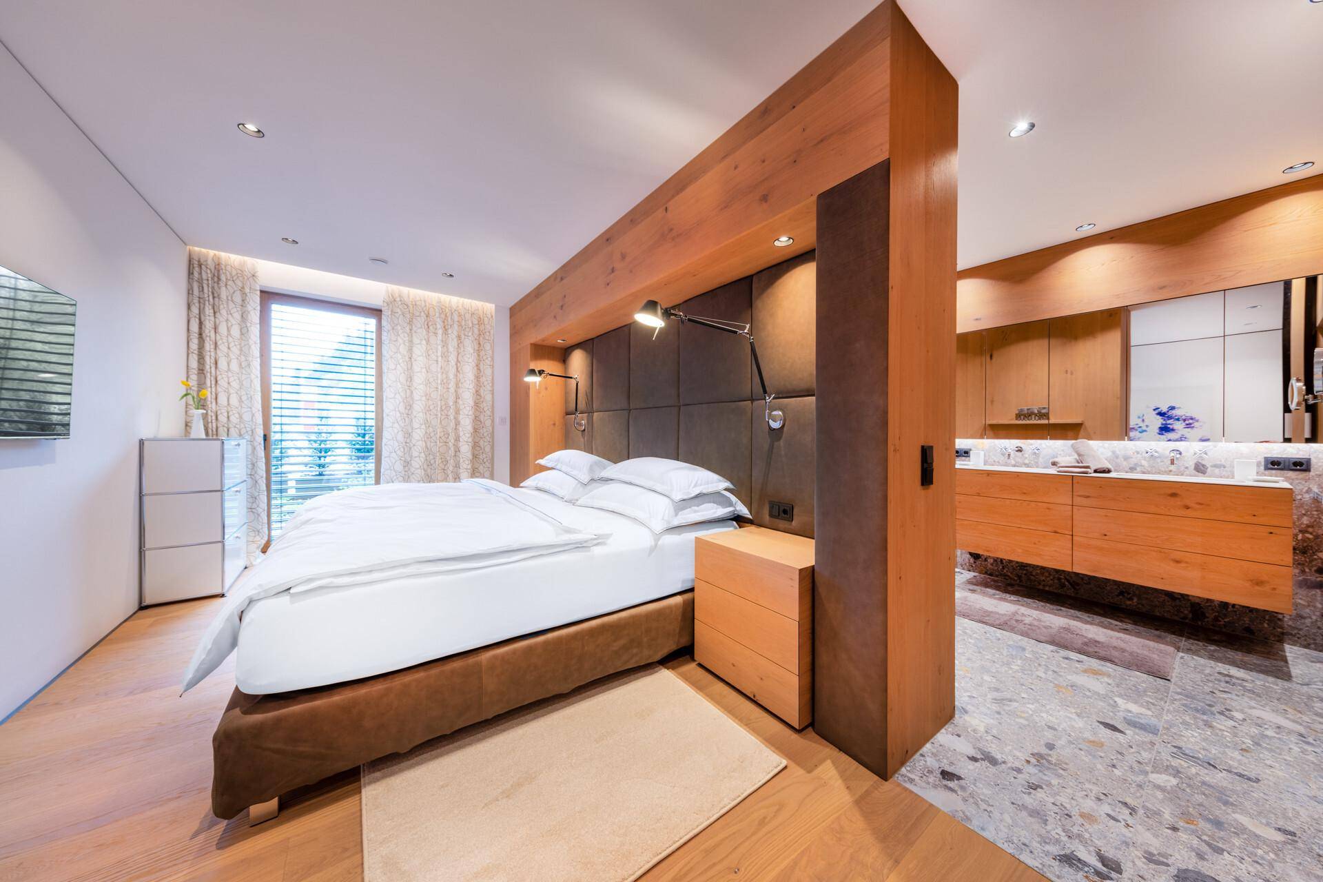 Geräumiges Schlafzimmer mit Holzboden, großem Bett und integriertem Waschtischbereich.