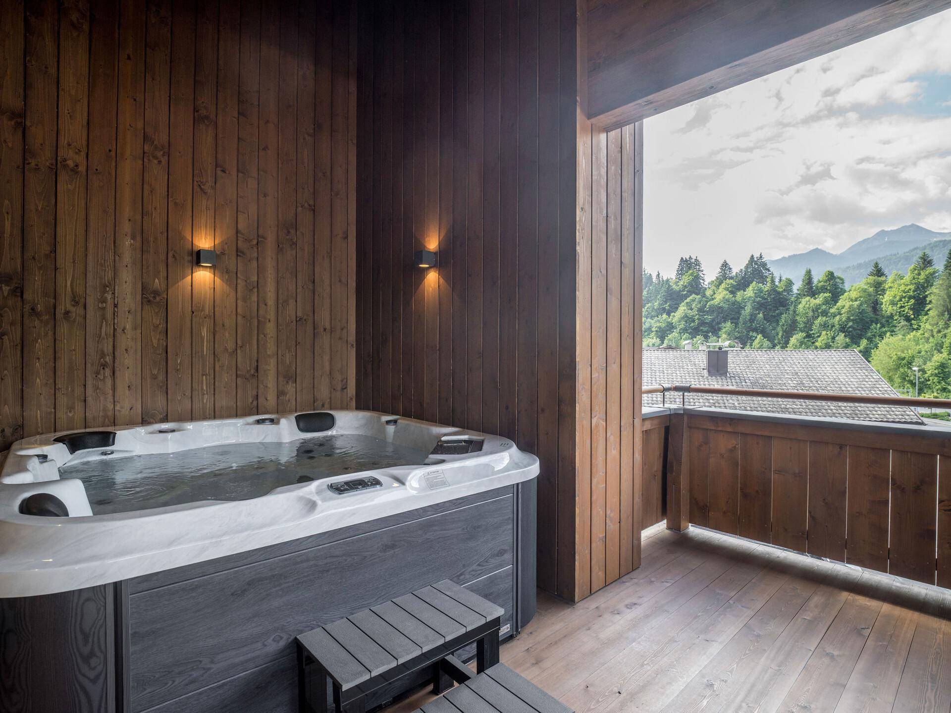 Großer Balkon mit Whirlpool und Holzwänden, bietet einen schönen Blick auf die Berge.