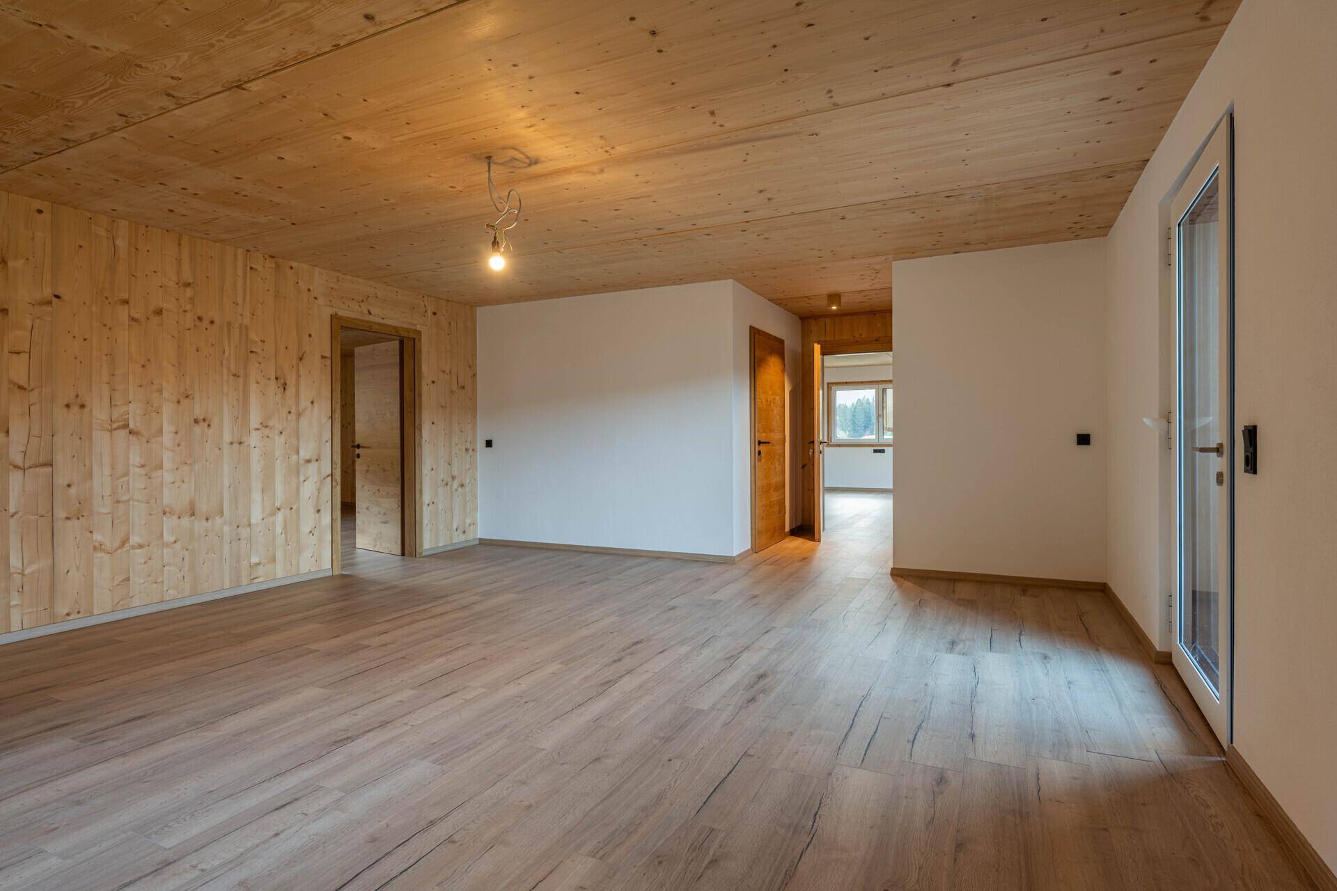 Geräumiger, unmöblierter Innenraum mit Holzwänden, Holzdecke und hellem Holzboden.
