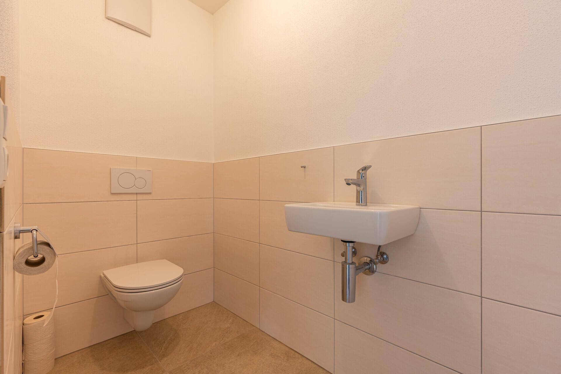 Helles Gäste-WC mit wandhängender Toilette und modernem Waschbecken.