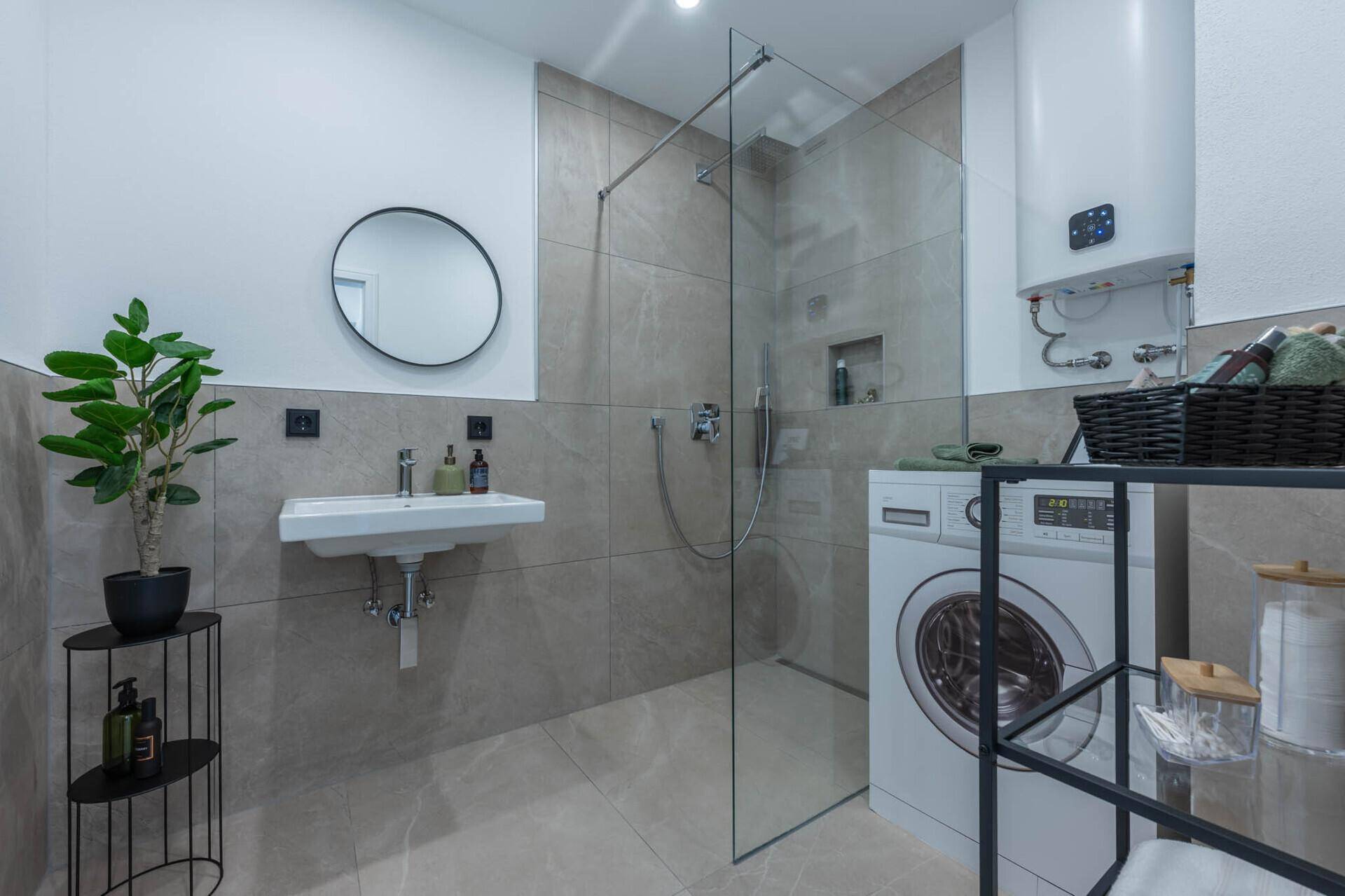 Modernes Badezimmer mit begehbarer Dusche, Waschbecken und Waschmaschine.