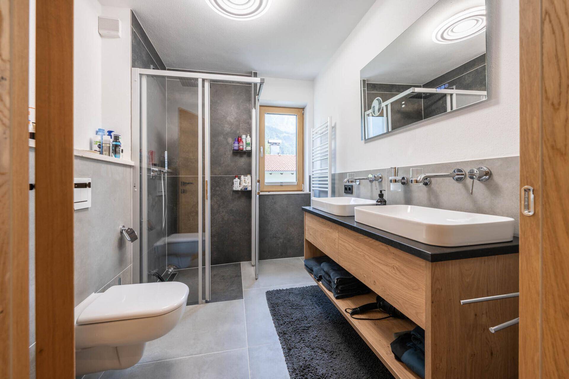 Modernes Badezimmer mit begehbarer Dusche, Doppelwaschbecken und Fenster für Tageslicht.