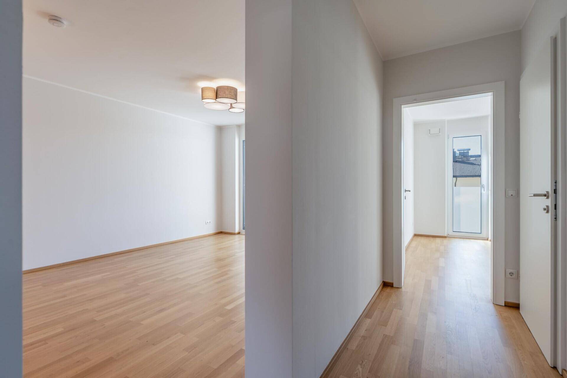 Heller Flur mit Holzboden, der zu den verschiedenen Räumen der Wohnung führt.