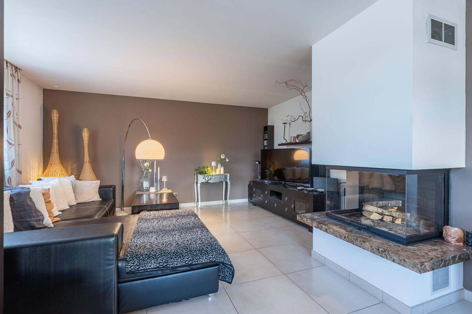 Gemütliches Wohnzimmer mit modernem Kamin, Fliesenboden und bequemen Ledersofas.