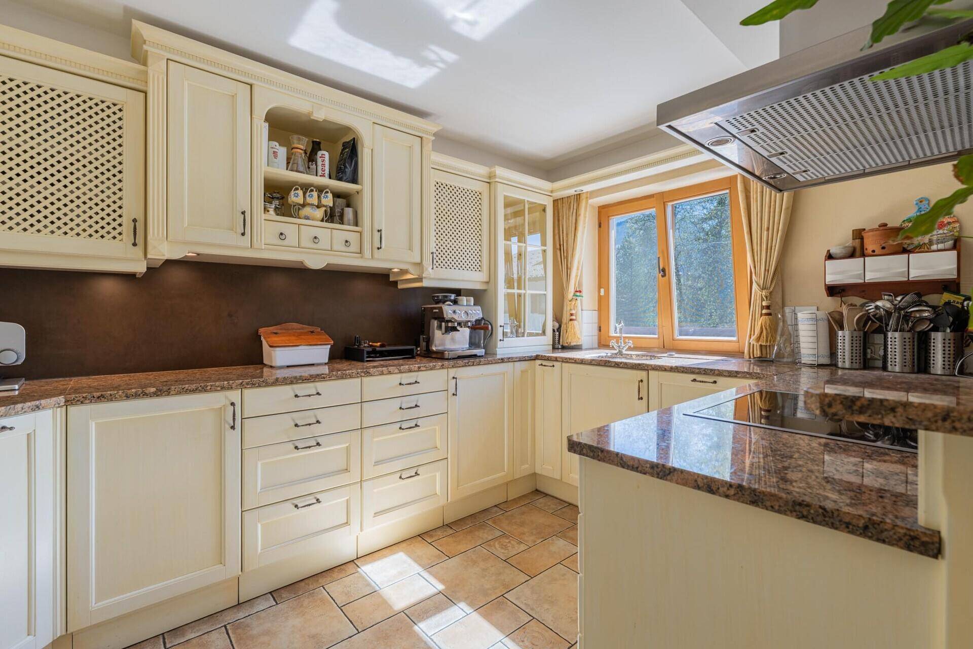 Traditionelle Küche mit hellen Schränken, Granitarbeitsplatten, Fenster und Fliesenboden.