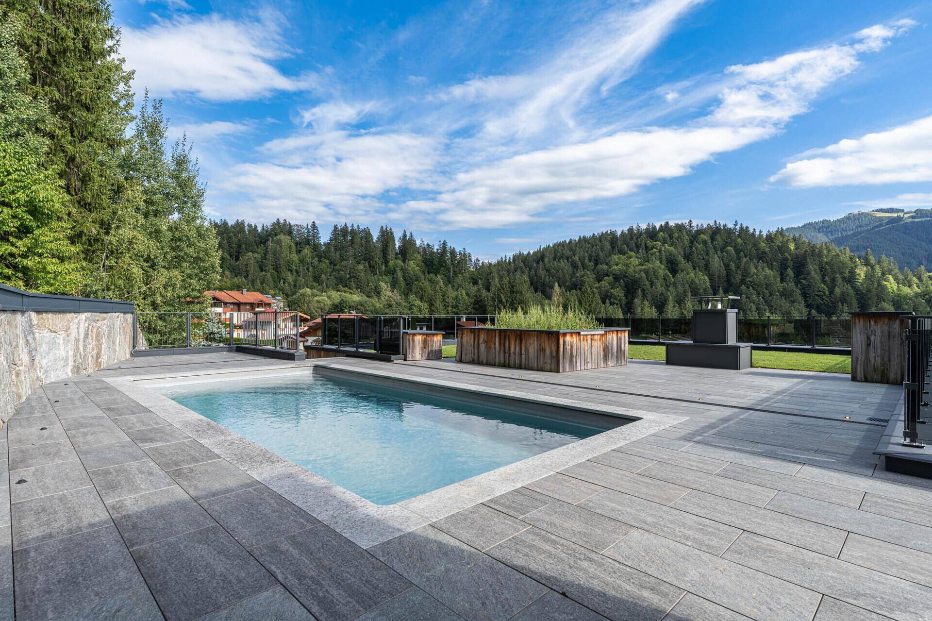 Große Dachterrasse mit Pool, Liegeflächen und Panoramablick auf die umliegende Berglandschaft.