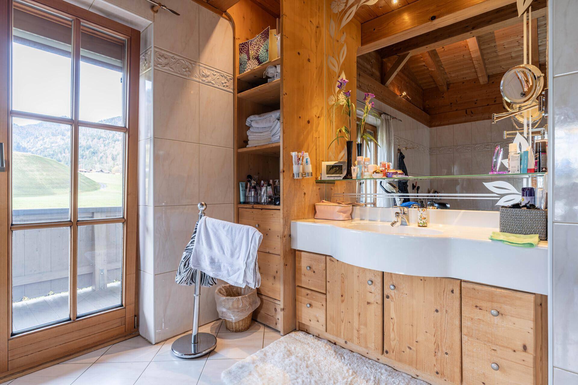 Badezimmer mit Holzwaschtisch, großem Fenster und malerischem Bergblick.