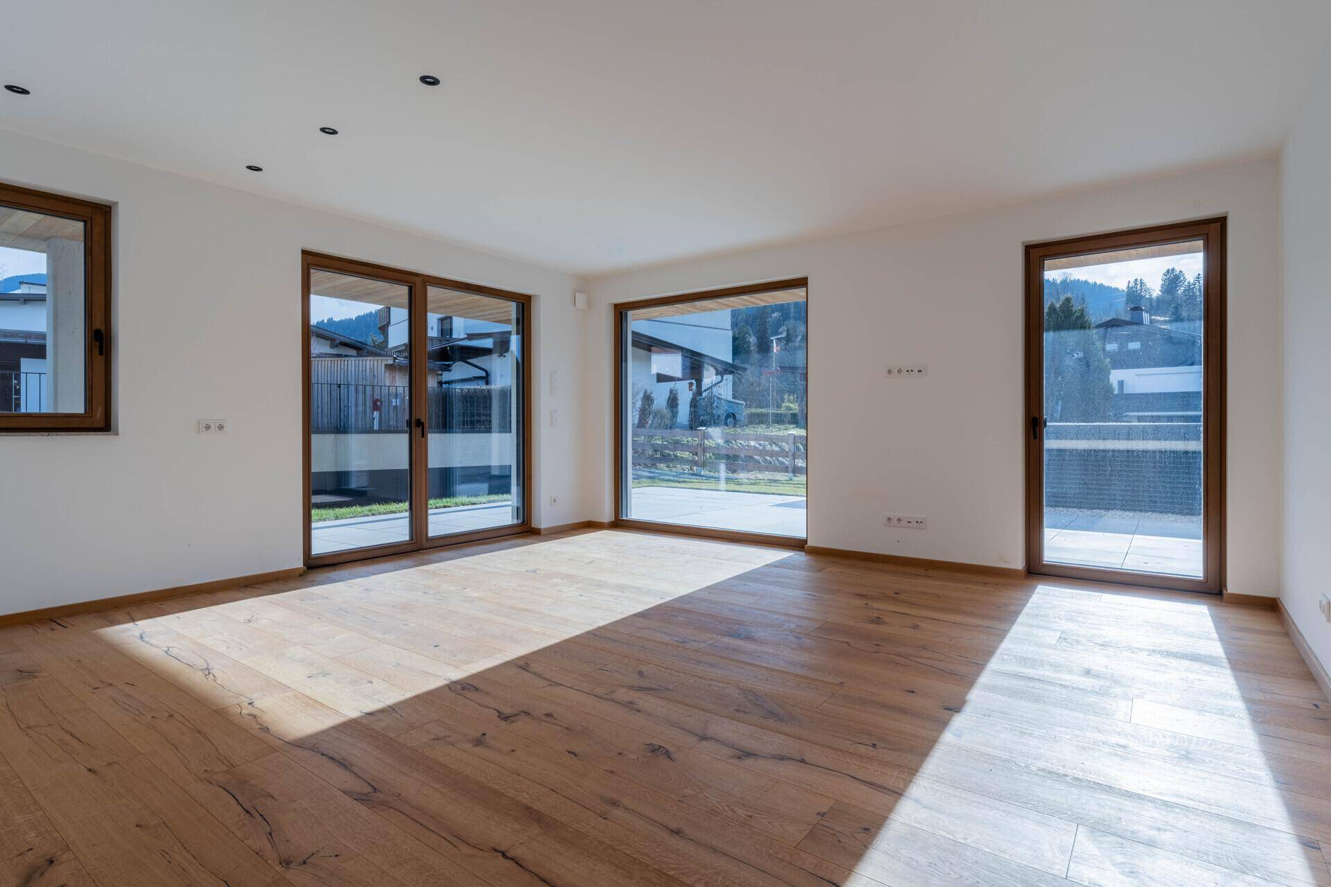 Geräumiger Wohnbereich mit viel Tageslicht, Holzboden und Zugang zur Terrasse.