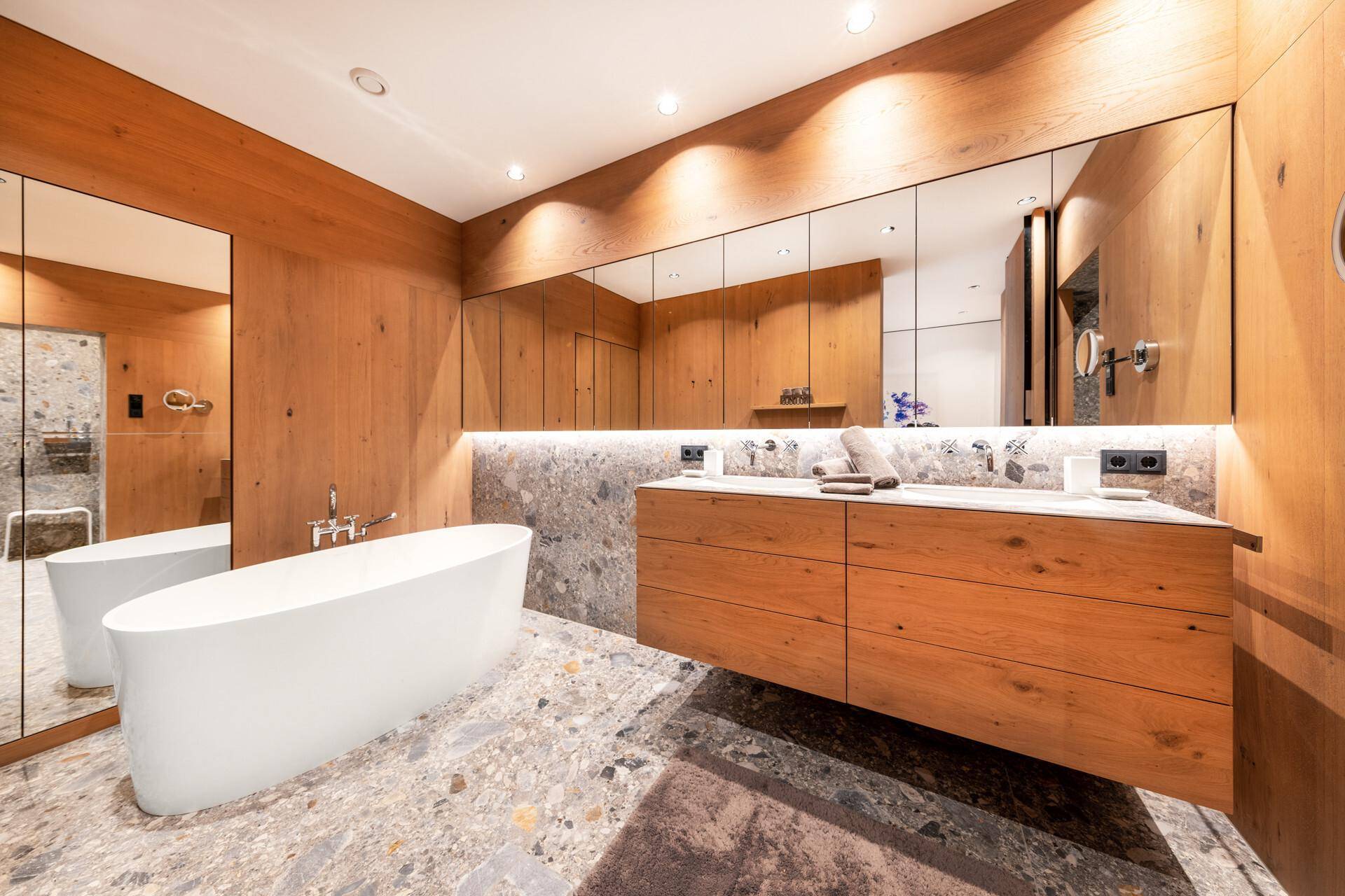 Luxuriöses Badezimmer mit freistehender Badewanne, Doppelwaschbecken und großem Spiegel.
