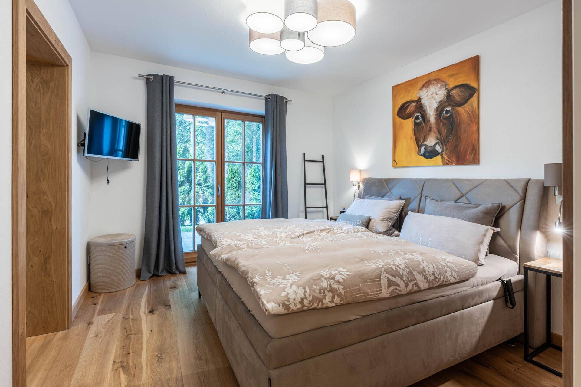 Gemütliches Schlafzimmer mit großem Bett, Holzboden und Zugang zum Außenbereich.