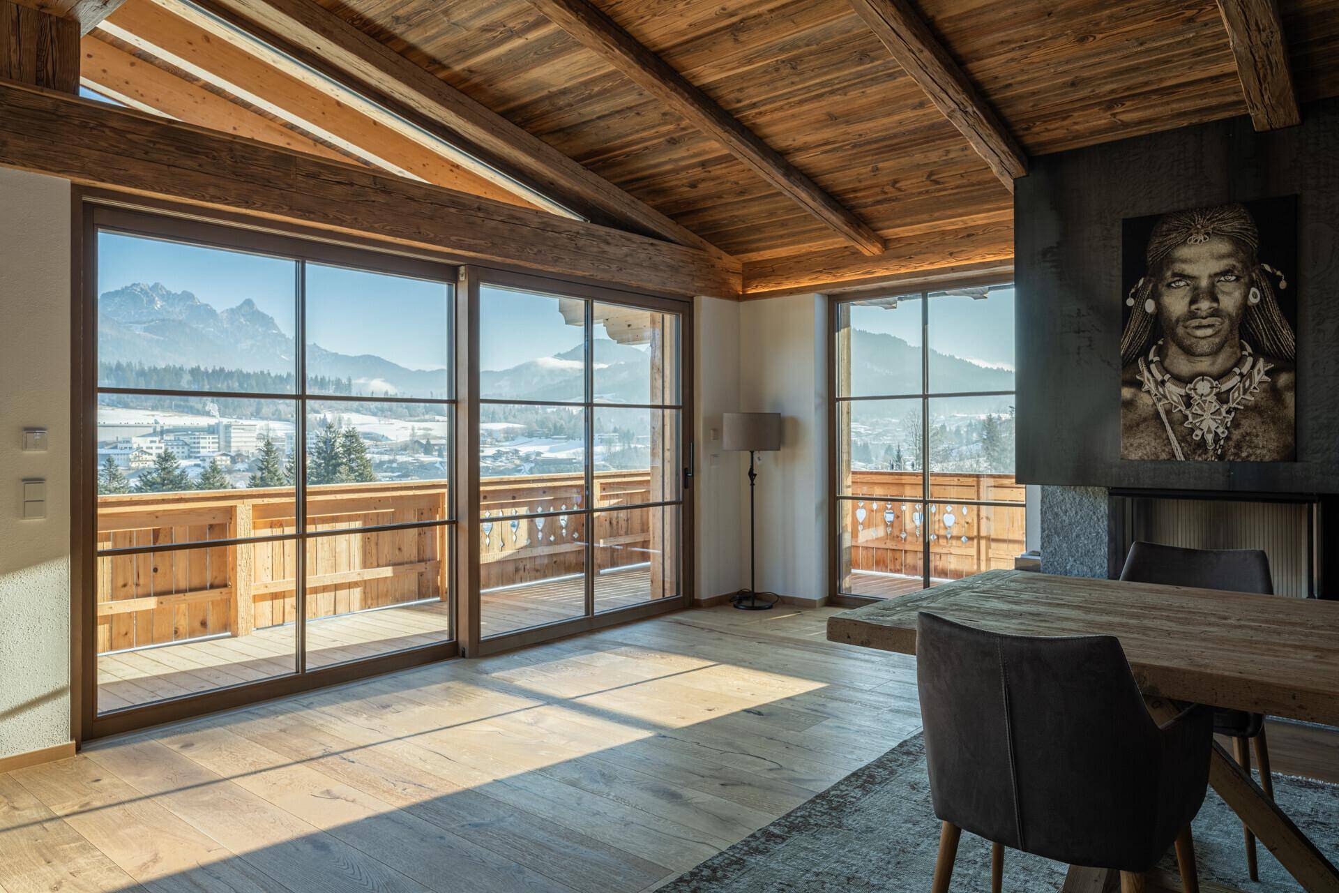 Lichtdurchfluteter Wohnbereich mit Zugang zum Balkon und Panoramablick auf die verschneite Berglandschaft.