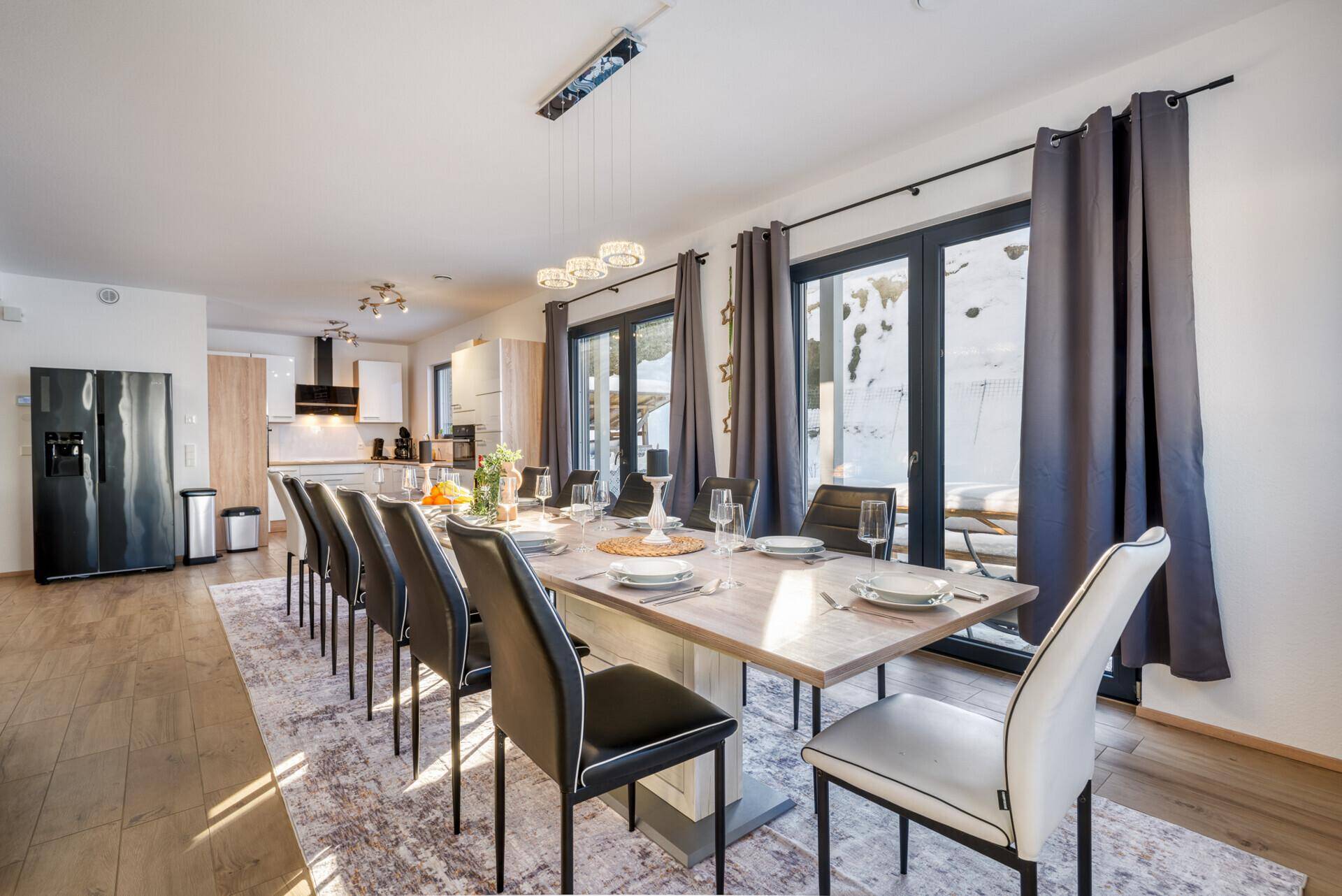 Geräumiger Essbereich mit langem Tisch und Zugang zur modernen Küche und Terrasse.