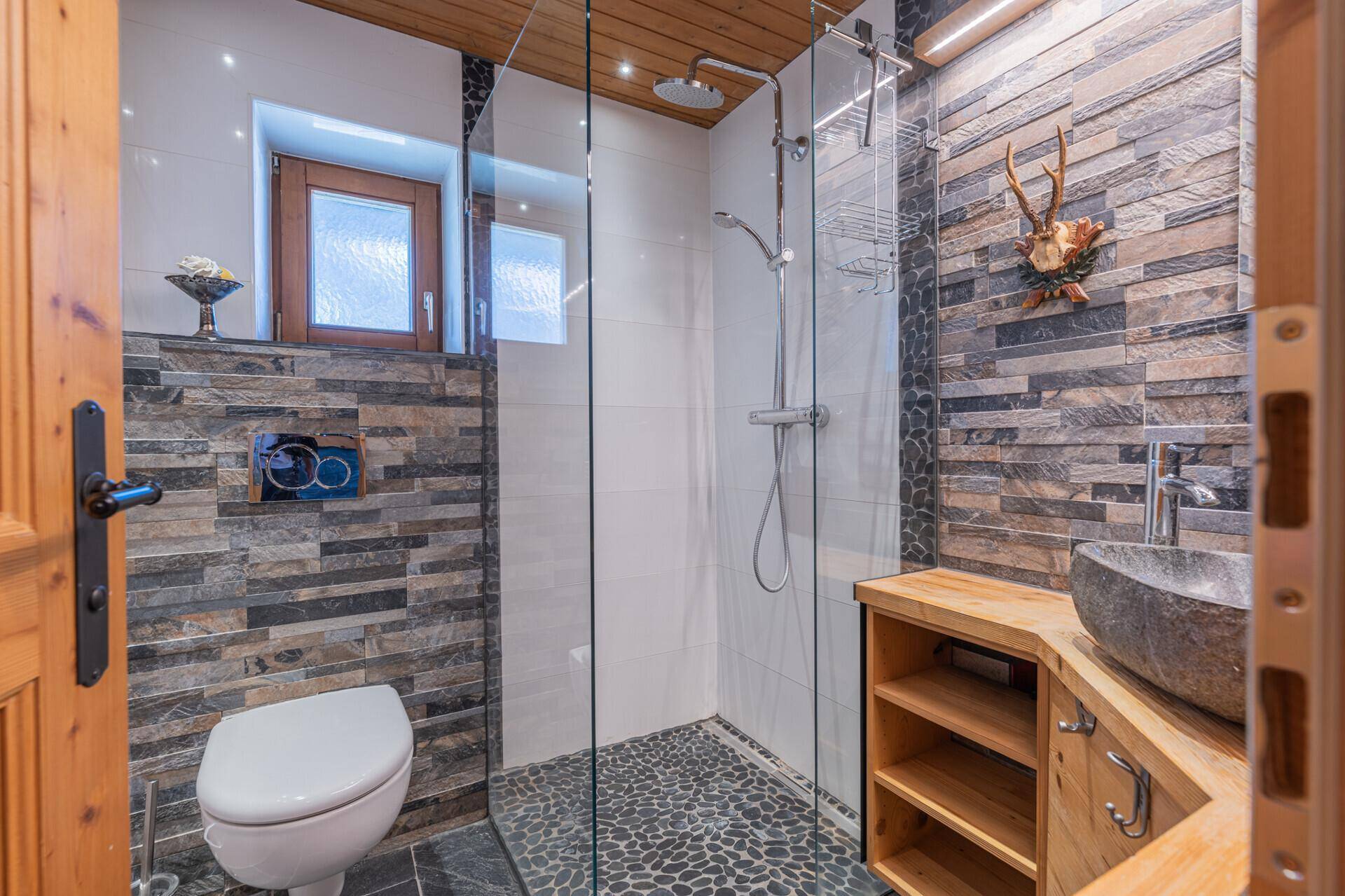Modernes Badezimmer mit begehbarer Dusche, Steinwaschbecken und Holzakzenten.