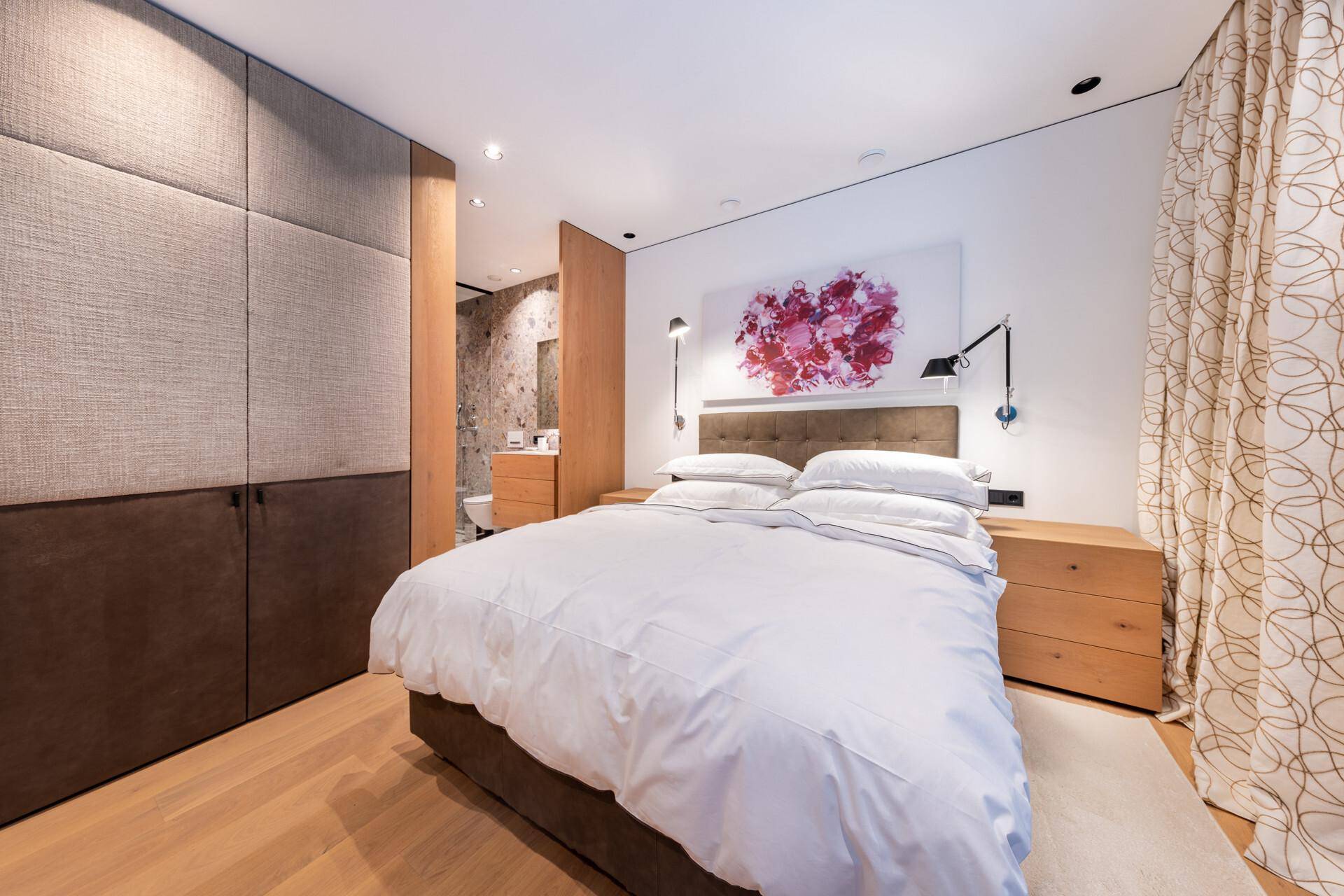 Komfortables Schlafzimmer mit großem Bett, Holzboden und integrierten Schränken.